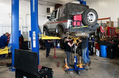 SUV lifted on a car hoist in an auto repair shop, with mechanics working underneath