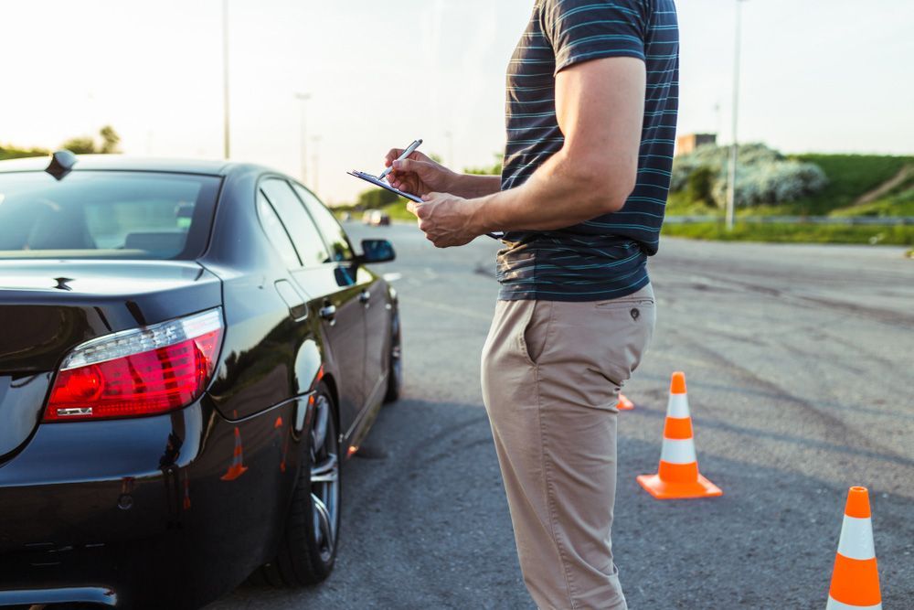 A Man Is Standing Next To A Car And Writing On A Clipboard β Darran Thompson Driver Training in Wollongong, NSW