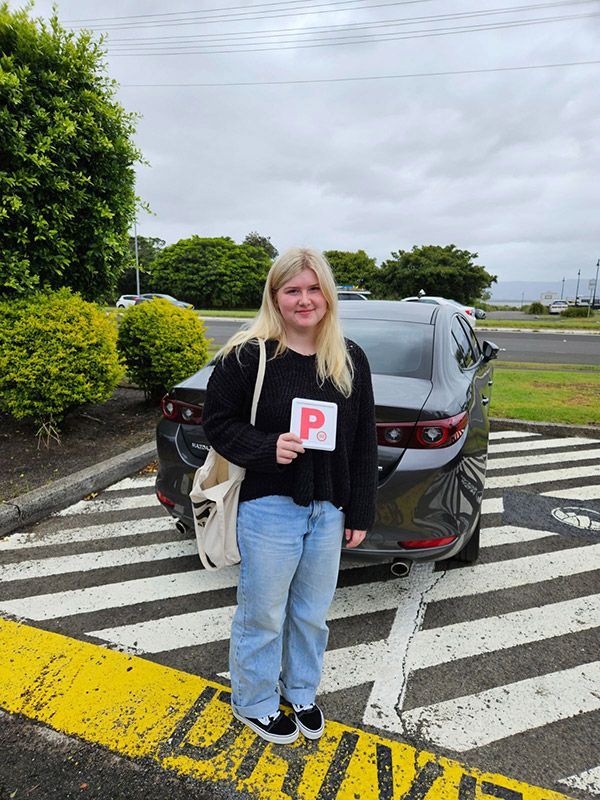 A Woman Is Standing In Front Of A Car Holding A P Letter Plate β Darran Thompson Driver Training in Wollongong, NSW