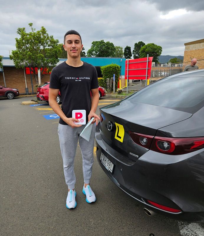 A Man Is Standing In Front Of A Car Holding Plate With The Letter P β Darran Thompson Driver Training in Wollongong, NSW