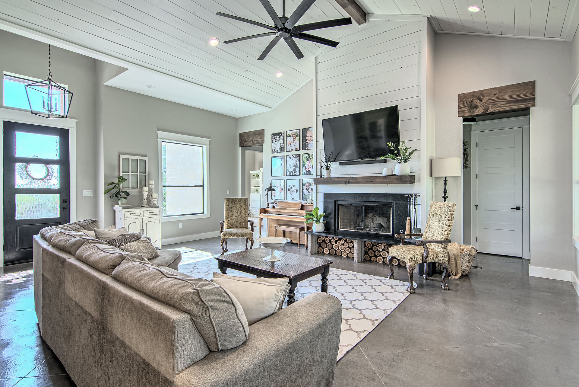 A living room with a couch , fireplace , television and ceiling fan.