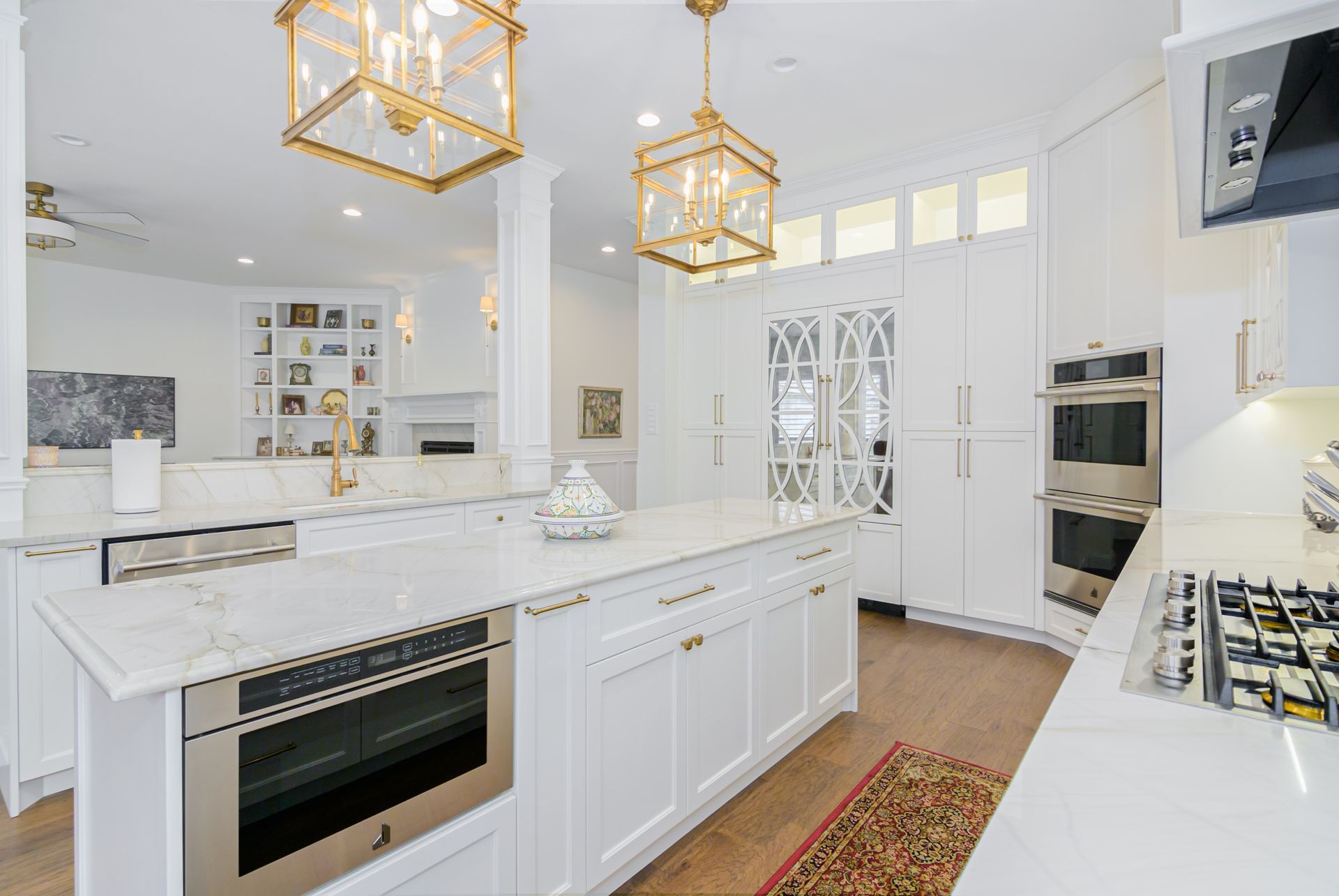 A kitchen with white cabinets , stainless steel appliances , and a large island.