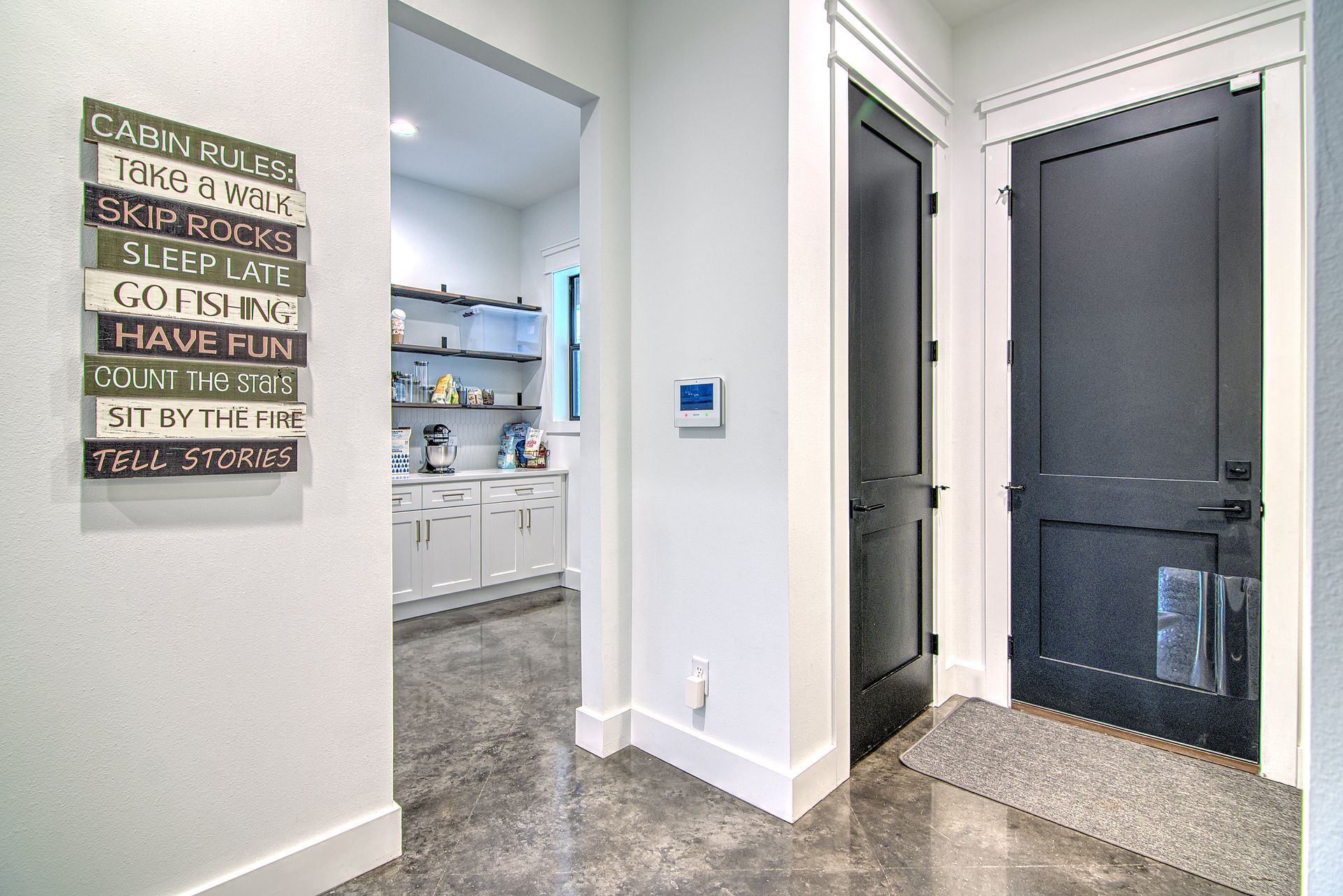 A hallway in a house with a black door and a sign on the wall.