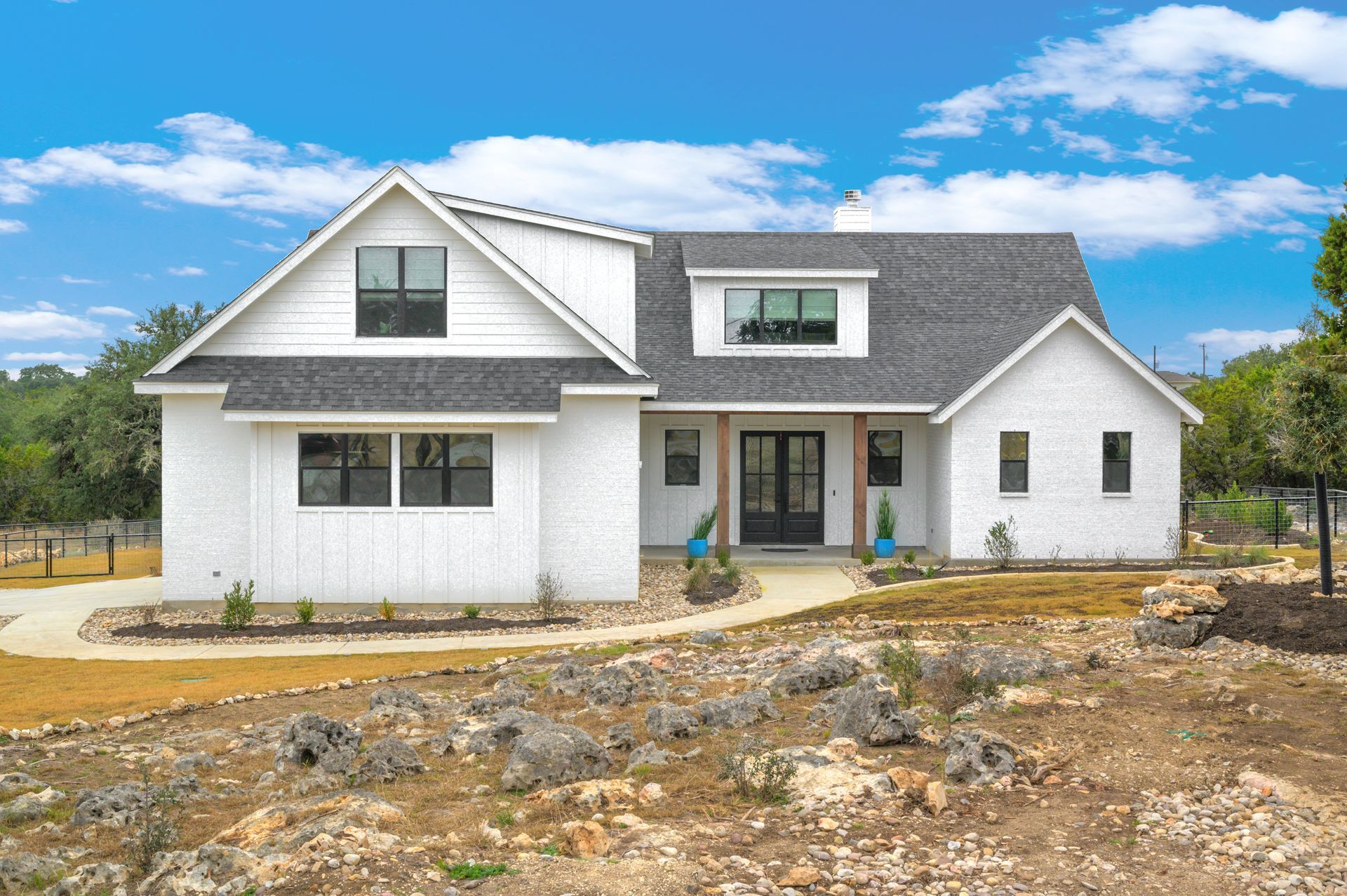 A white house with a gray roof is sitting on top of a dirt hill.