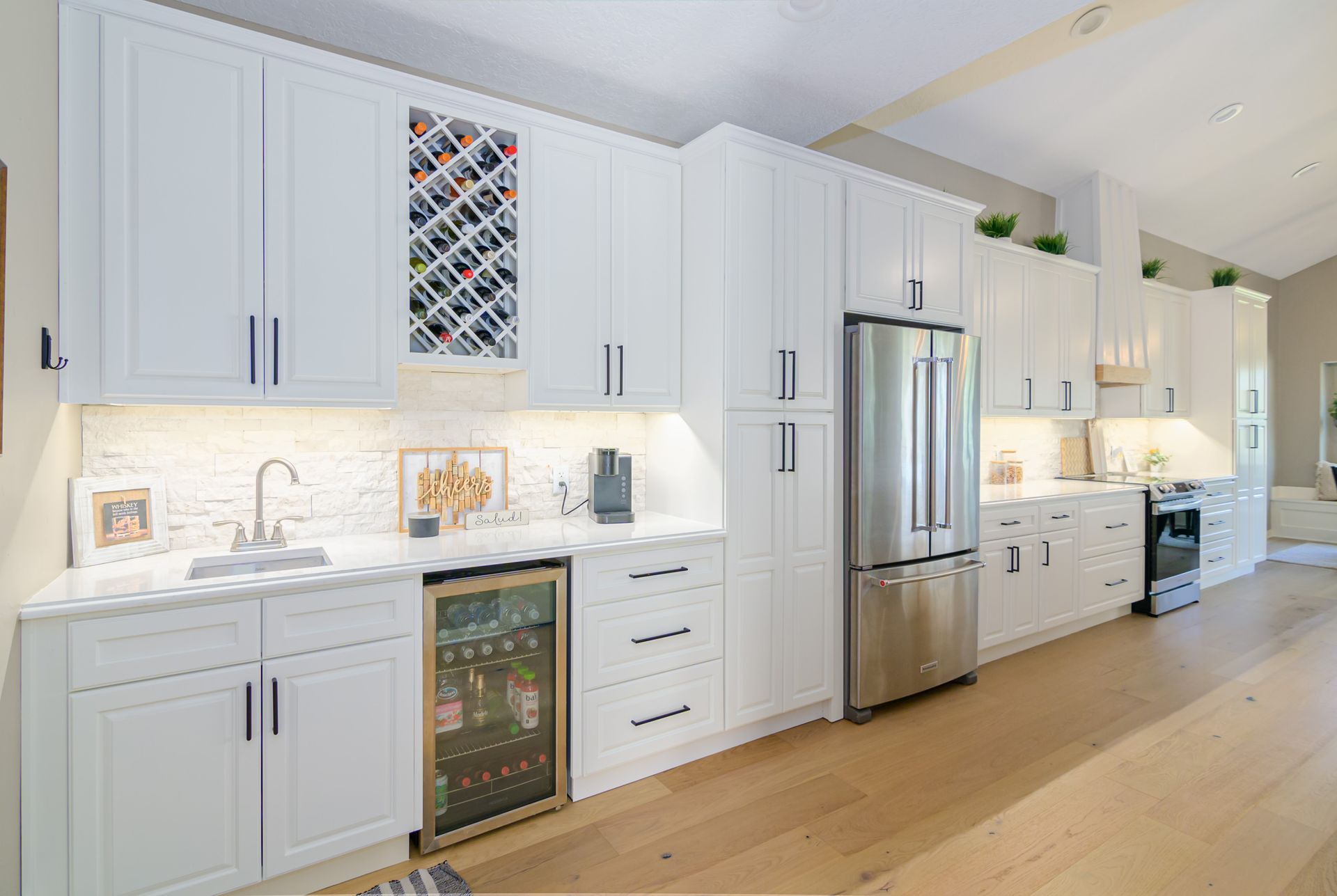 A kitchen with white cabinets , stainless steel appliances and a wine cooler.
