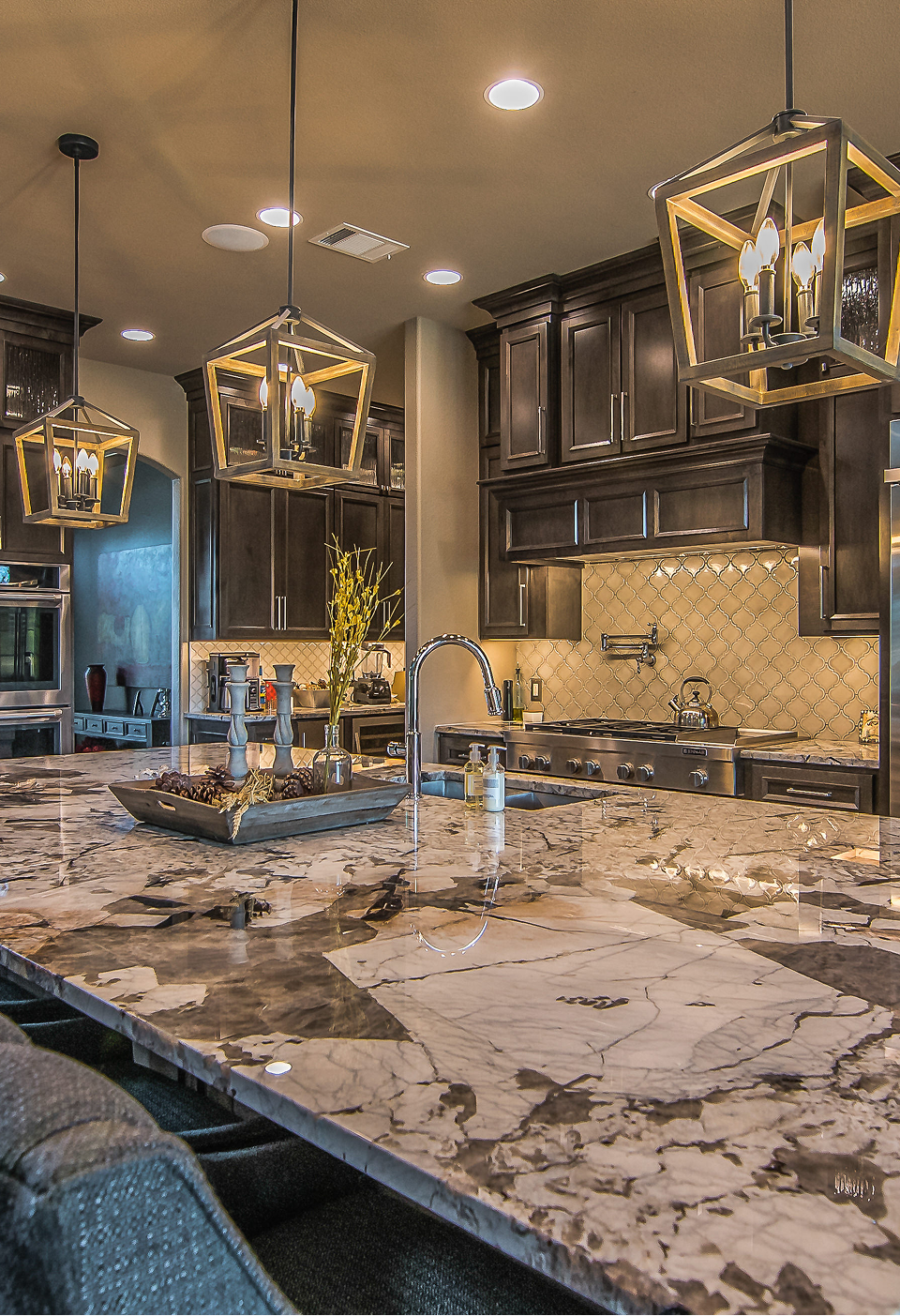 A kitchen with white cabinets , black counter tops , and a large island.