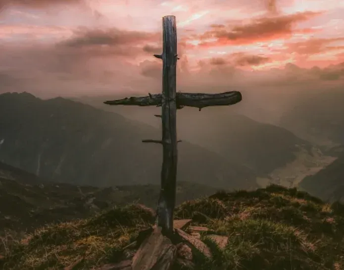 A wooden cross is sitting on top of a mountain.