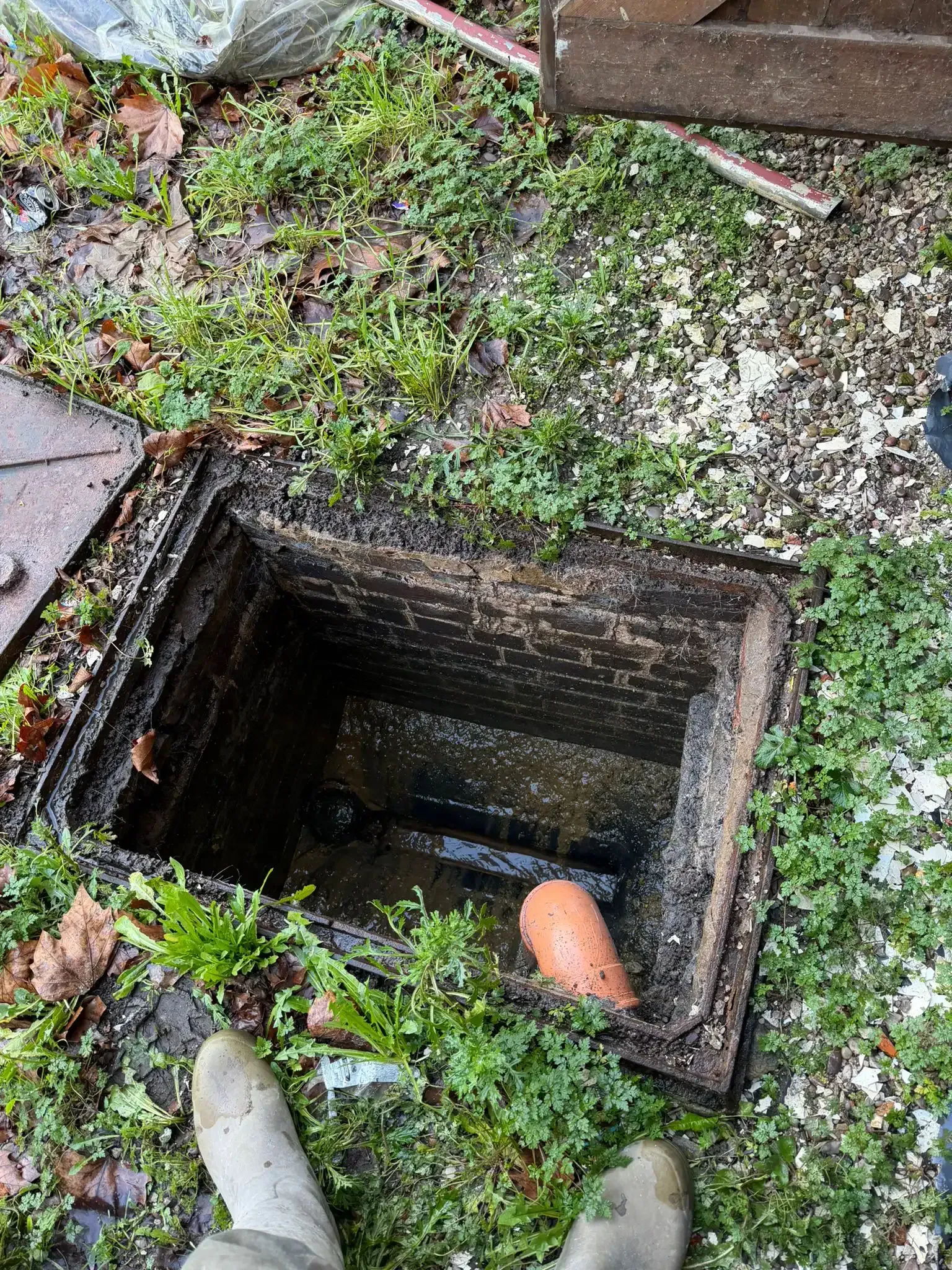 Icy water dripping from a metal downspout, creating a frozen column; snow on the ground.