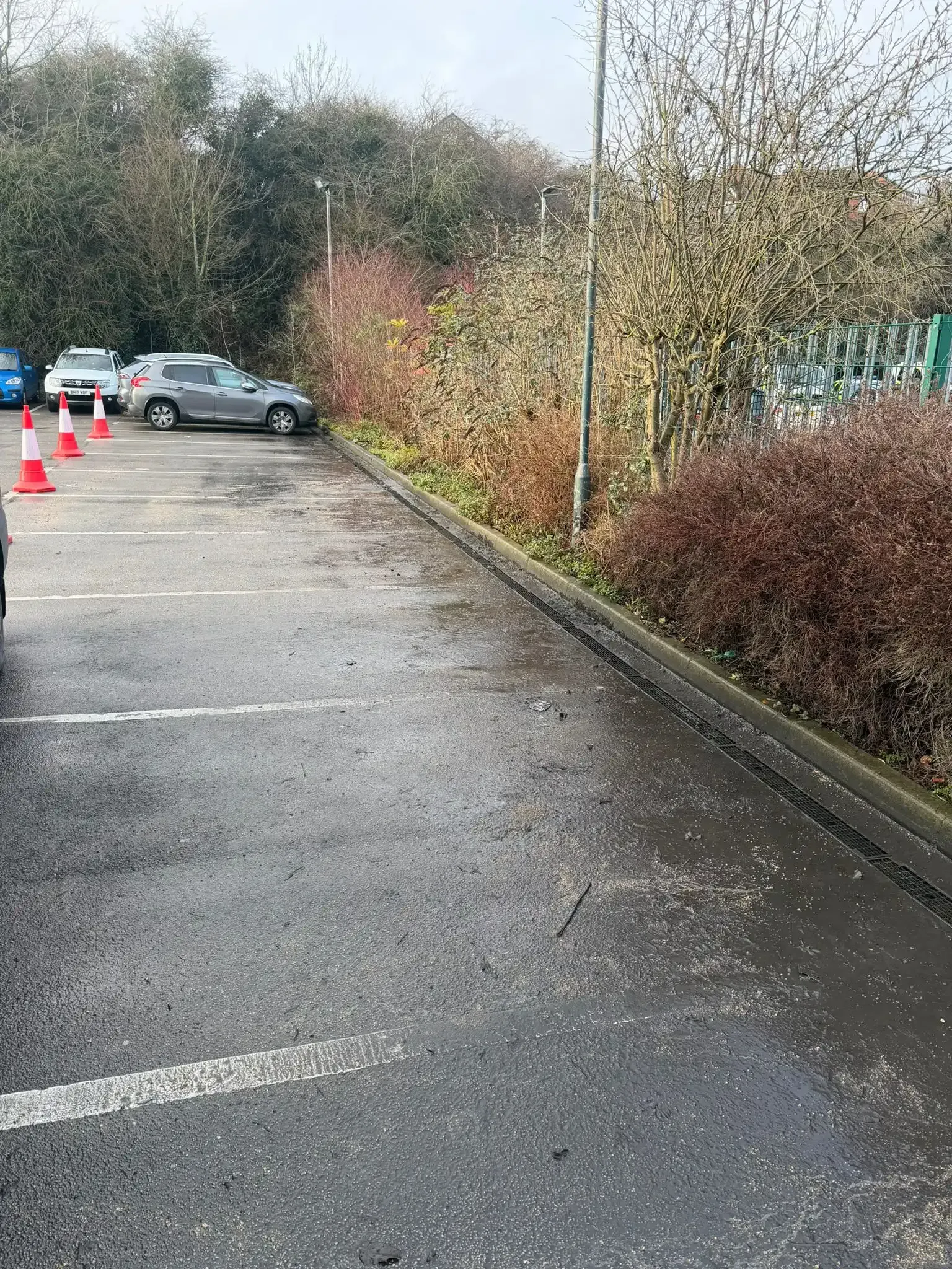 Gray pipe secured to a corrugated white wall with a metal clamp; shadows on right.