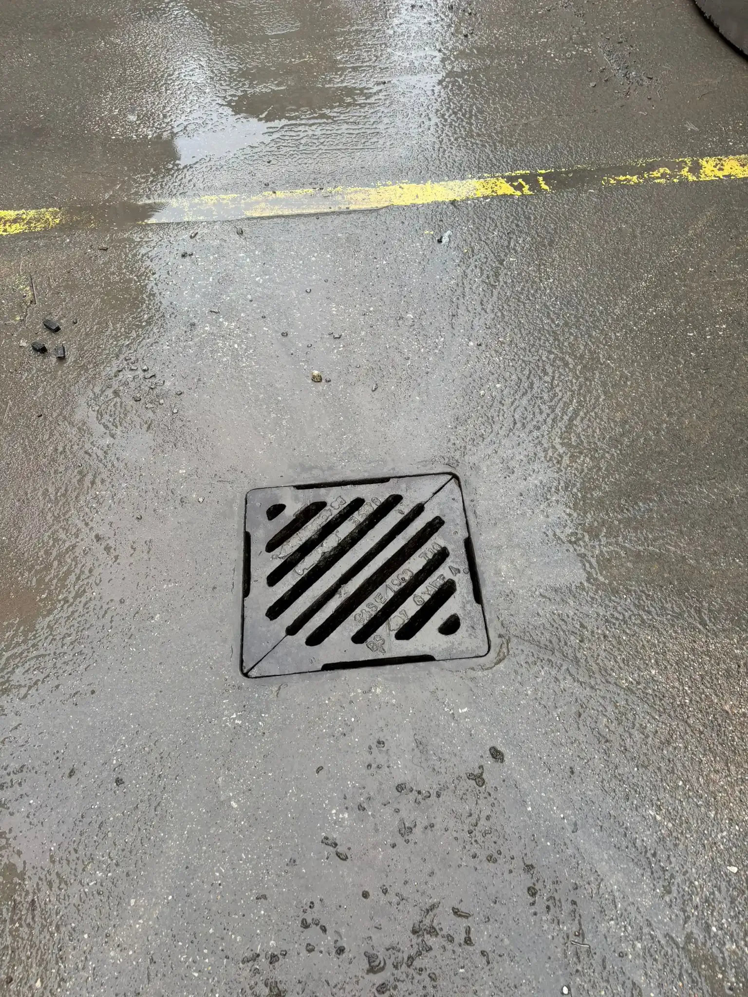Gray pipe secured to white corrugated metal siding with a metal clamp.