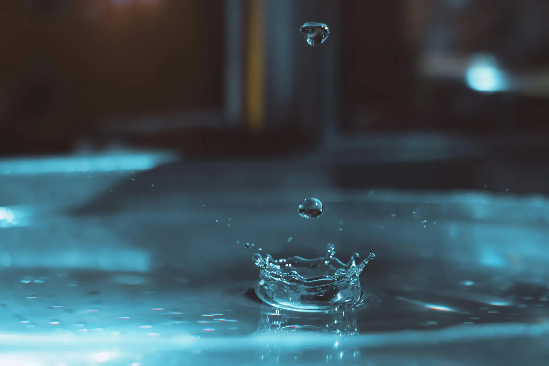 Icicle hanging from a metal downspout, snow on the ground and building.
