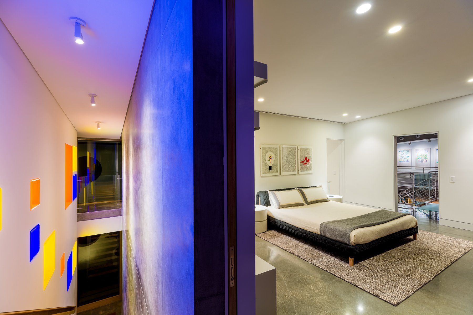 Bedroom with a bed and rug, and a hallway with colorful wall accents.