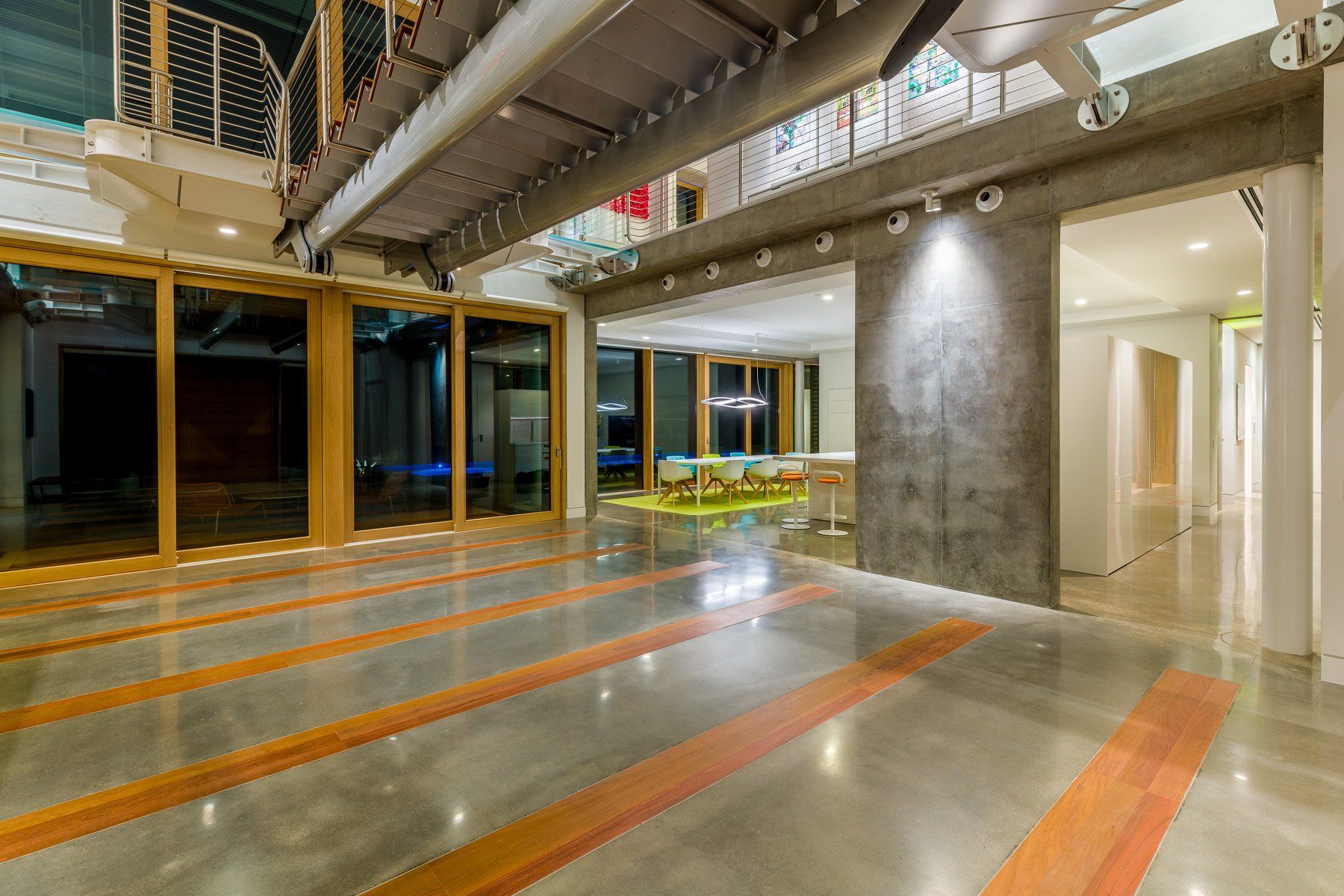 Spacious modern home interior with polished concrete floors and large windows, featuring exposed beams and a walkway.