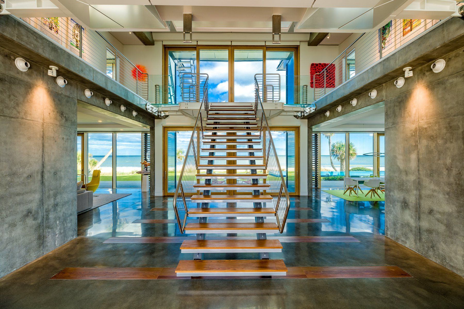 Spacious entryway with a floating staircase, large windows overlooking the ocean.