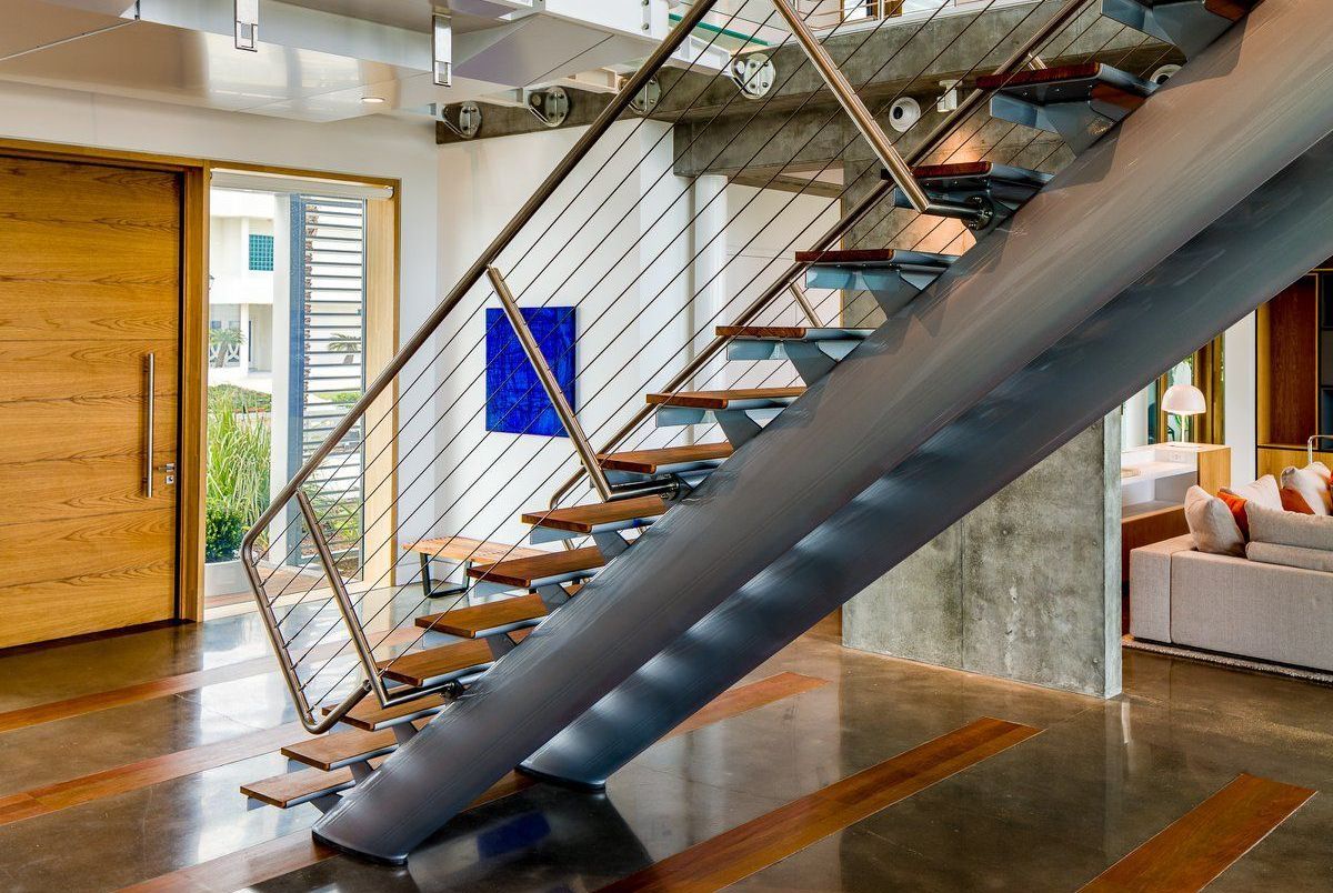 A modern staircase with wooden steps and a metal railing in a living room.