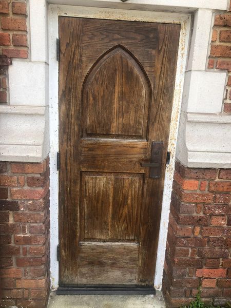 Wooden arched door set in a red brick and white stone facade.