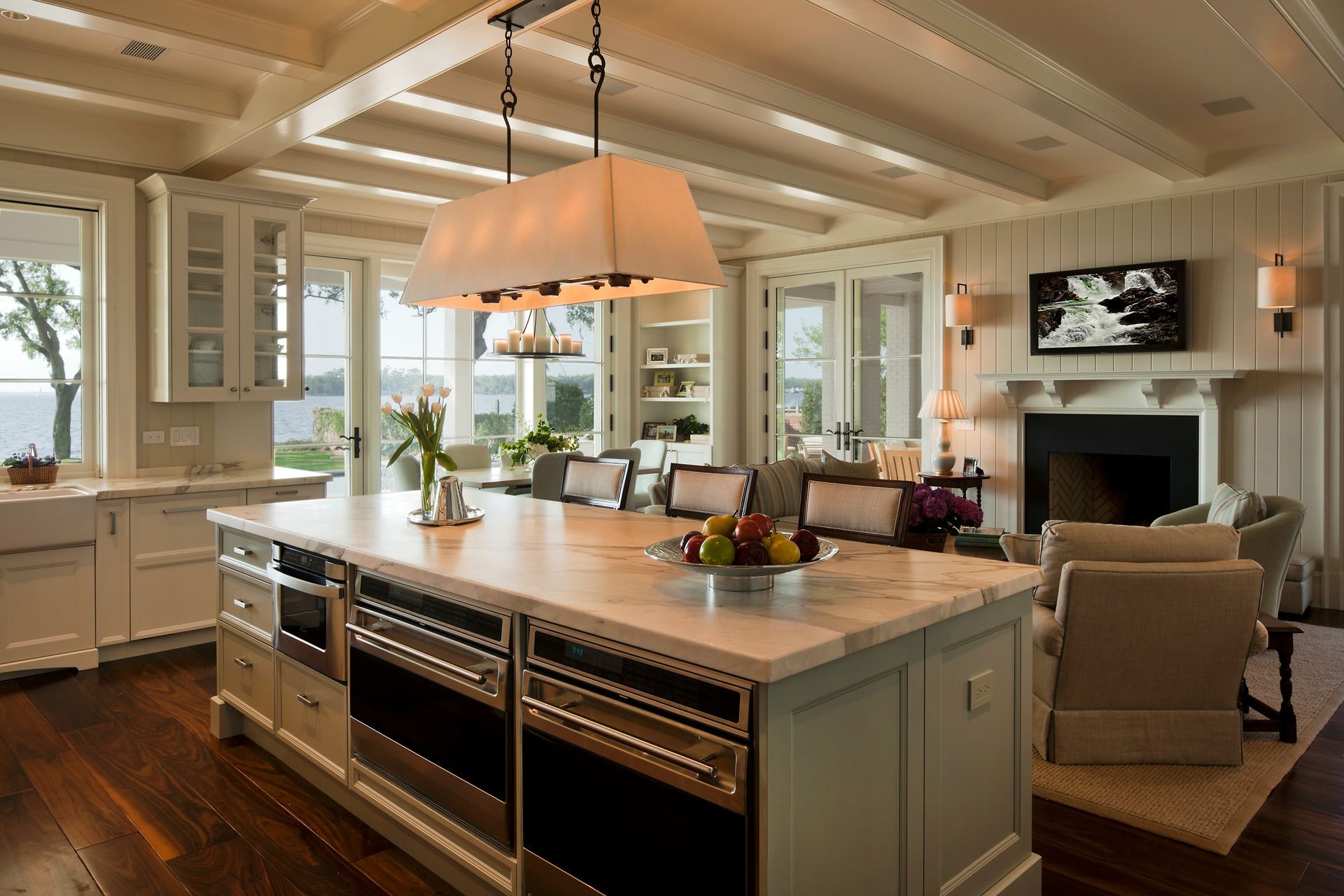 Spacious kitchen with island, marble countertops, stainless steel appliances, and adjacent living area with fireplace.