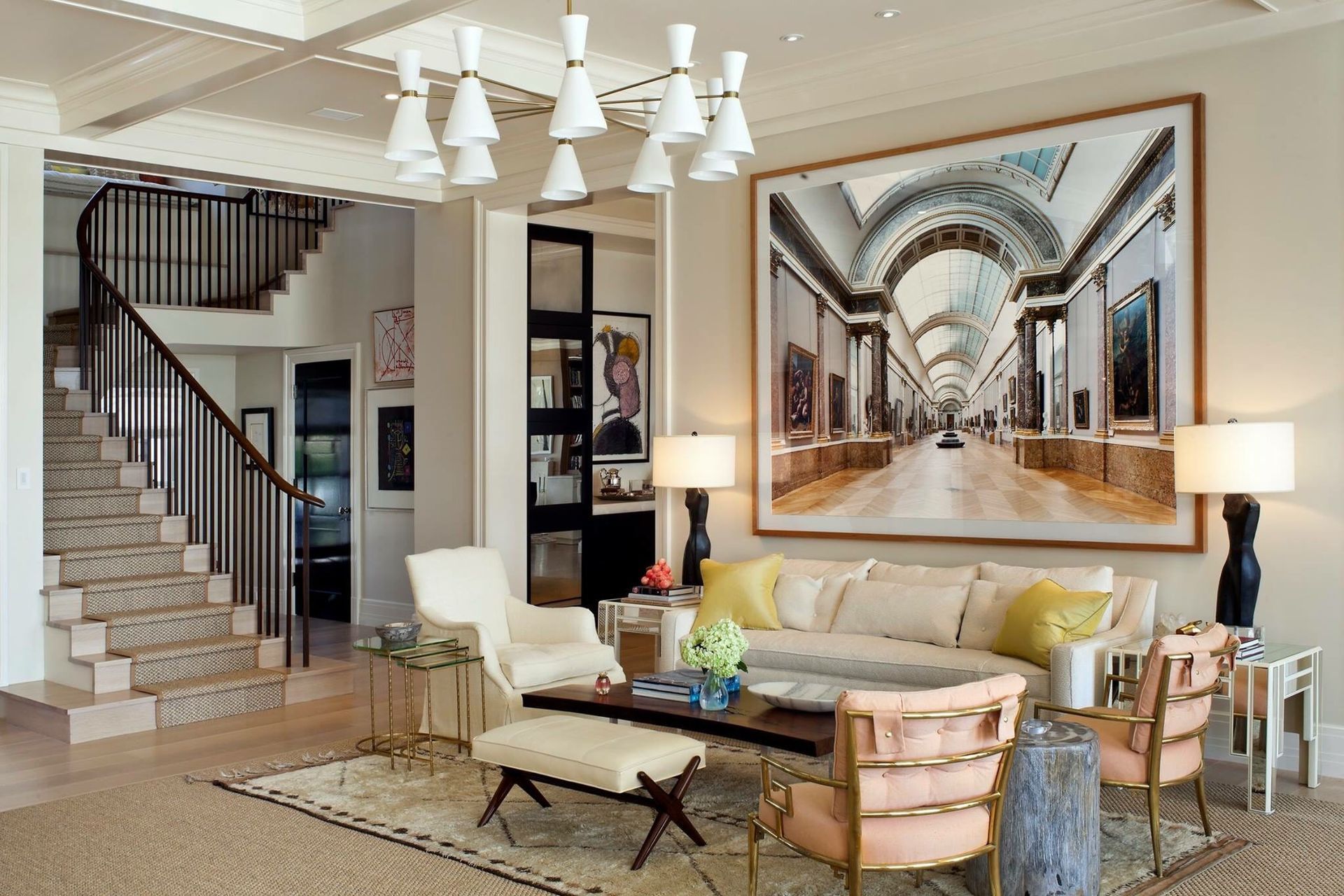 Elegant living room with staircase, artwork, white sofa, and unique chandelier.