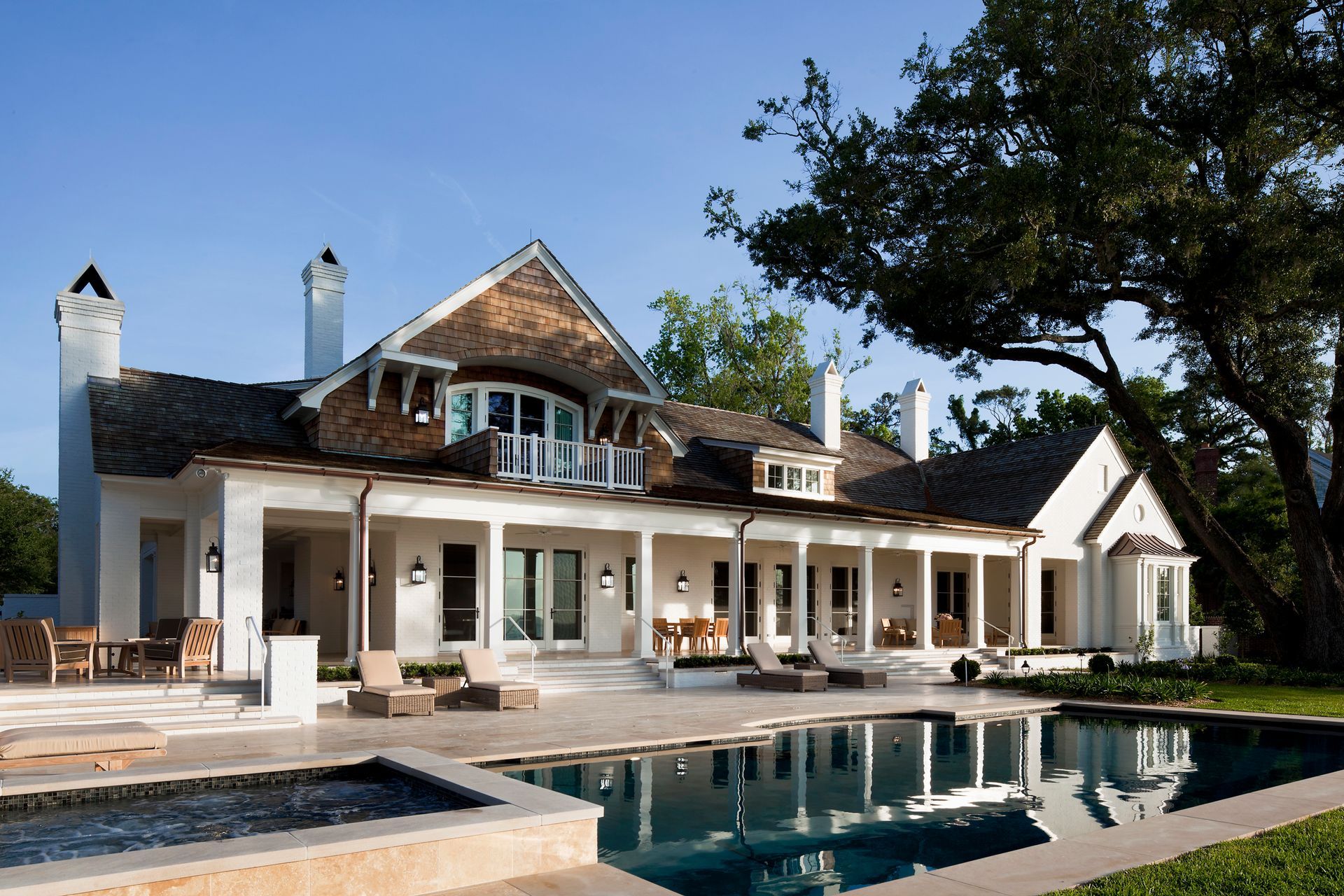 White stucco house with pool, porch, and wood accents, under a blue sky.