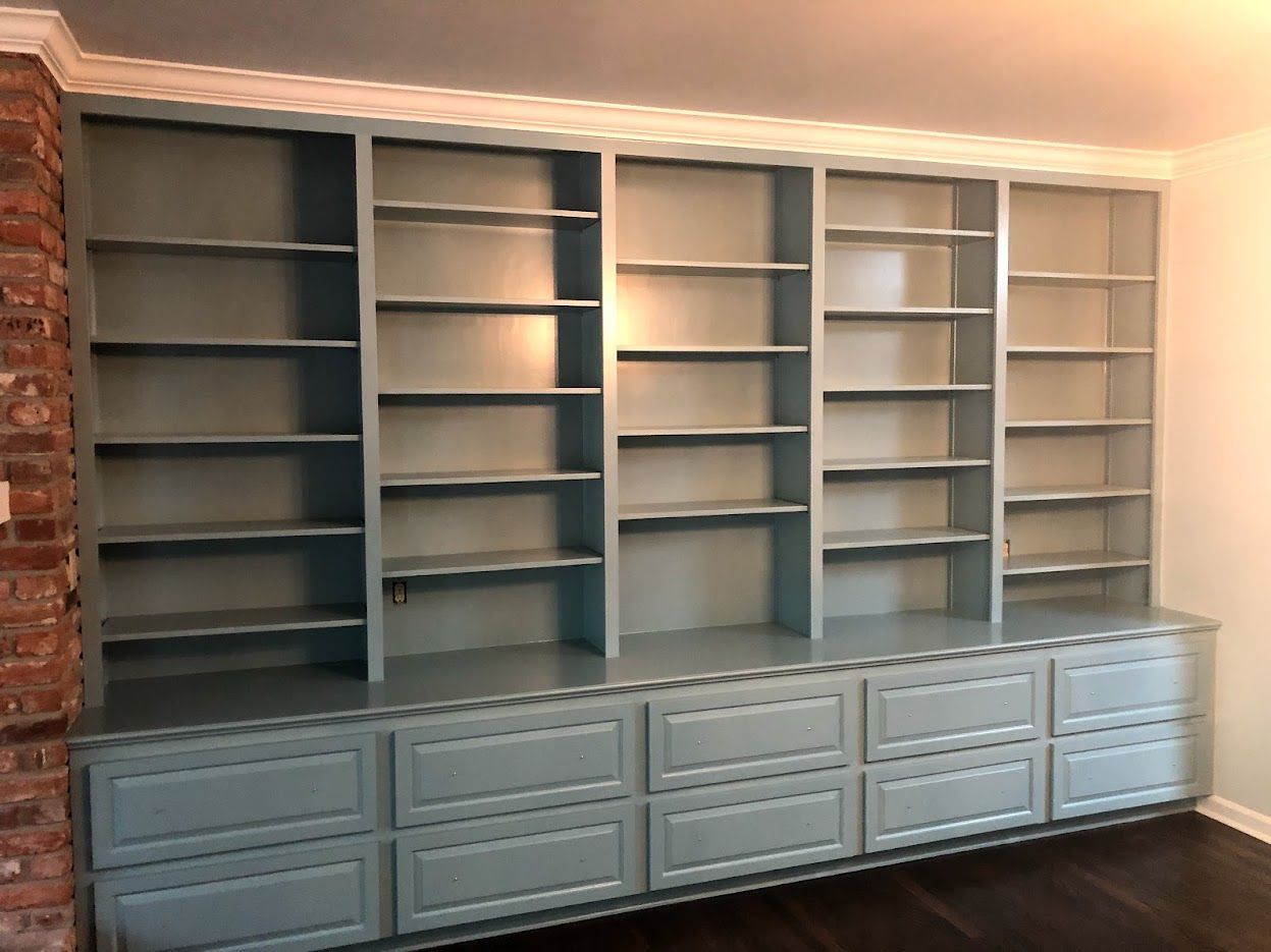 Built-in blue bookshelves with lower cabinets against brick and white walls.