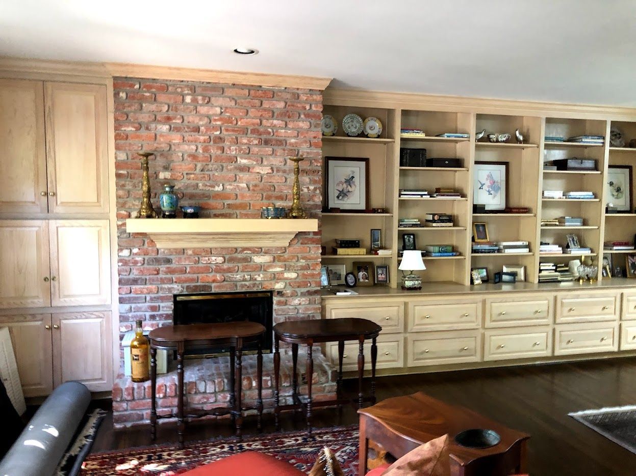 Living room with brick fireplace, built-in shelves, and wooden cabinets.