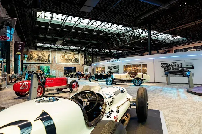 Race cars on display at a museum. Interior shot with multiple vintage vehicles and informational displays.