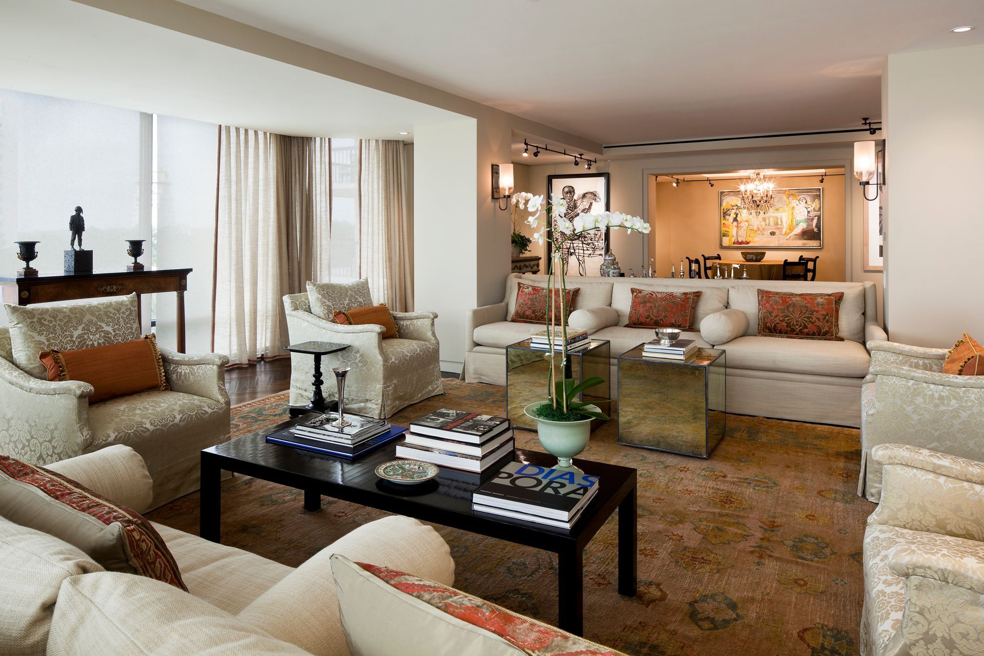 Beige and orange living room with couches, coffee table, and a view of the dining area.