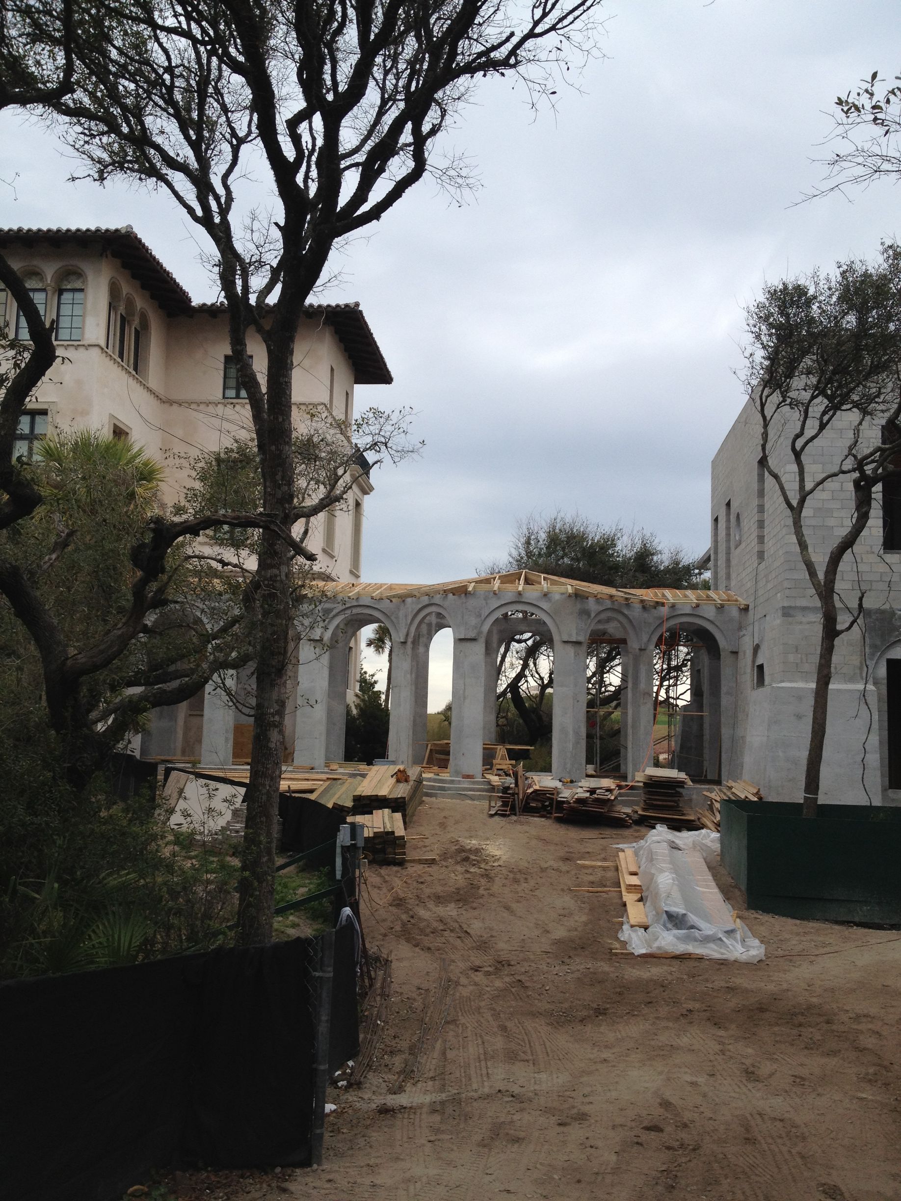 Building under construction with arched columns and scaffolding.