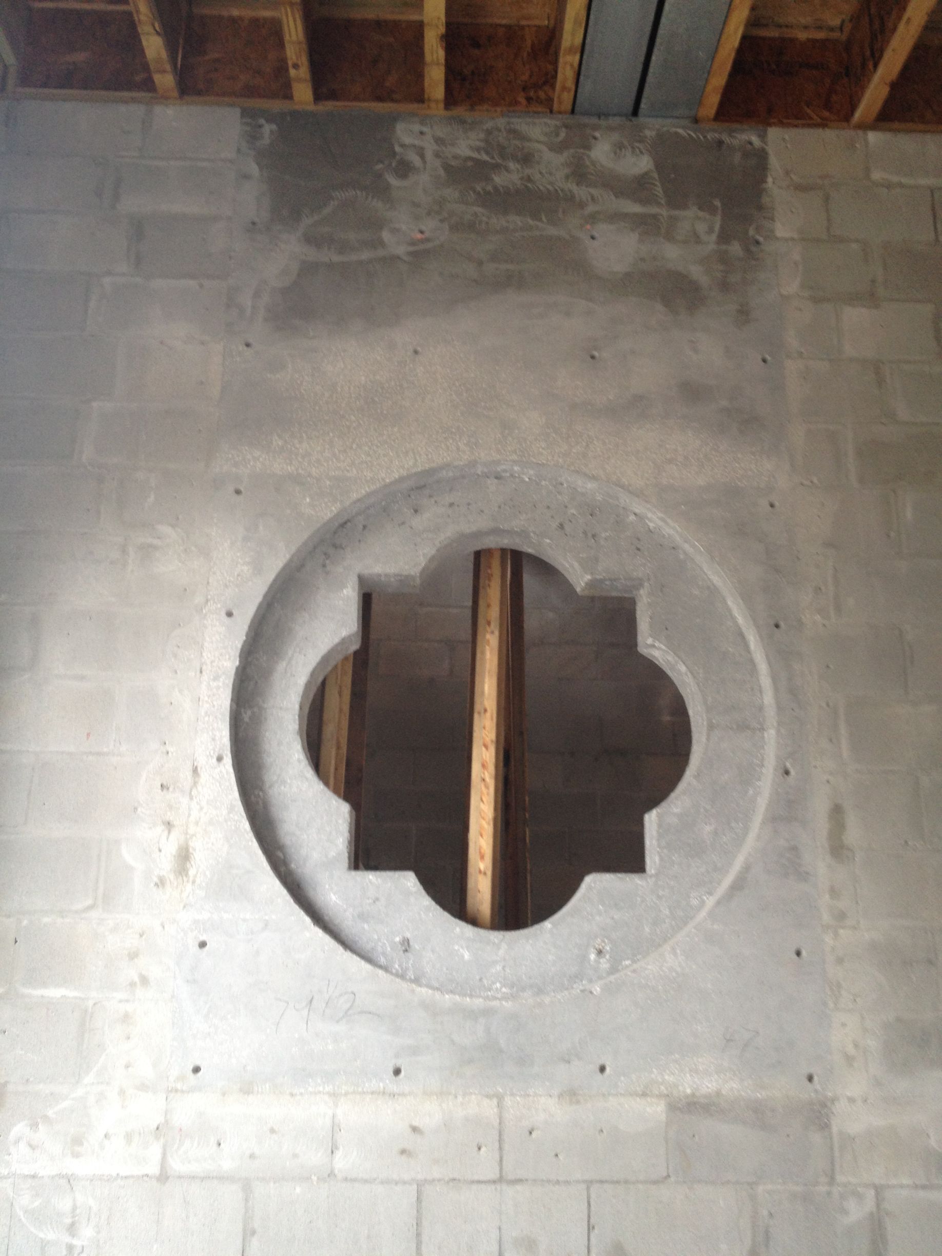 Concrete block wall with round decorative opening. Exposed wooden beams above.
