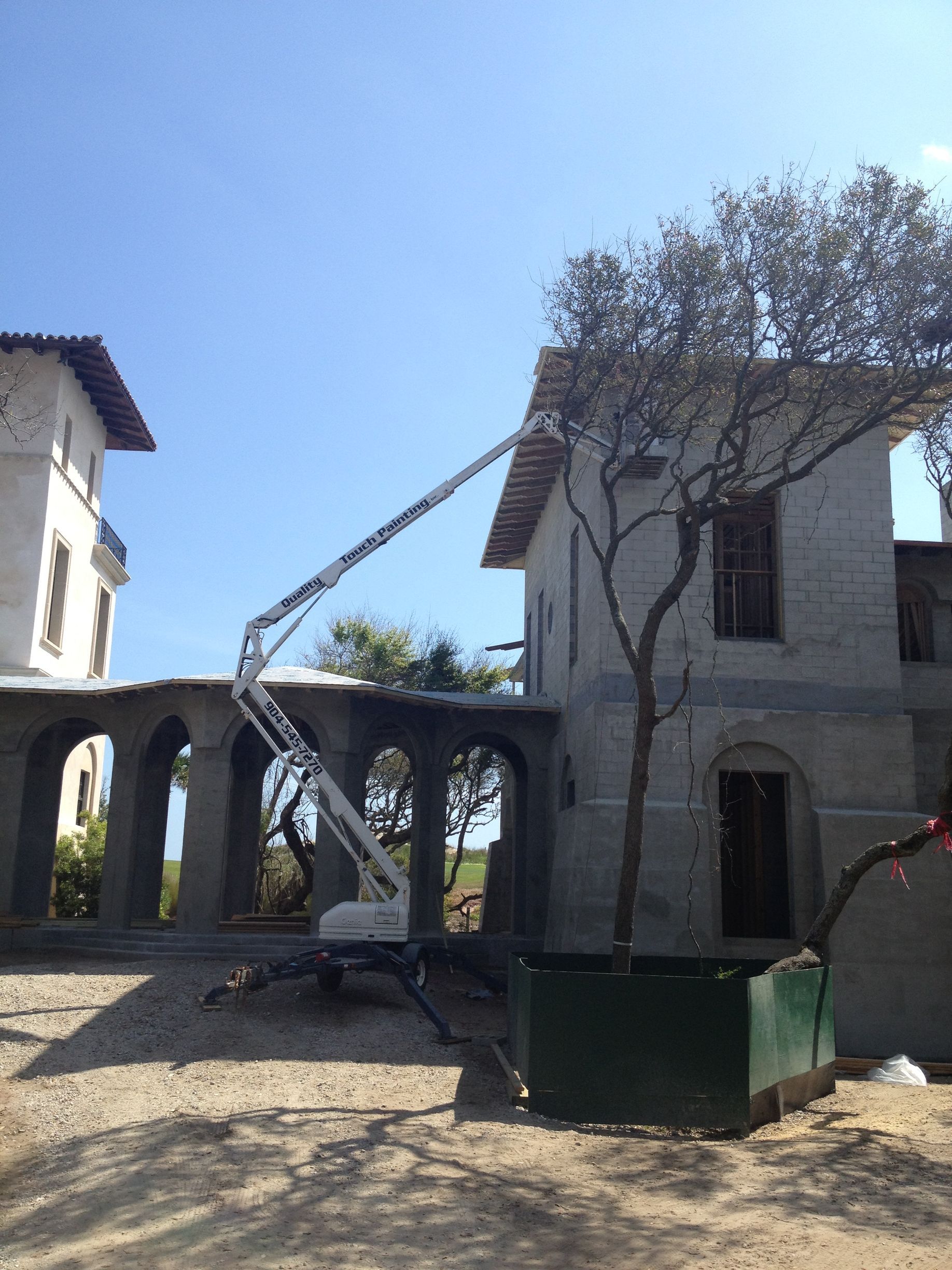 Construction site with an aerial lift next to a building. Sunny, blue sky.
