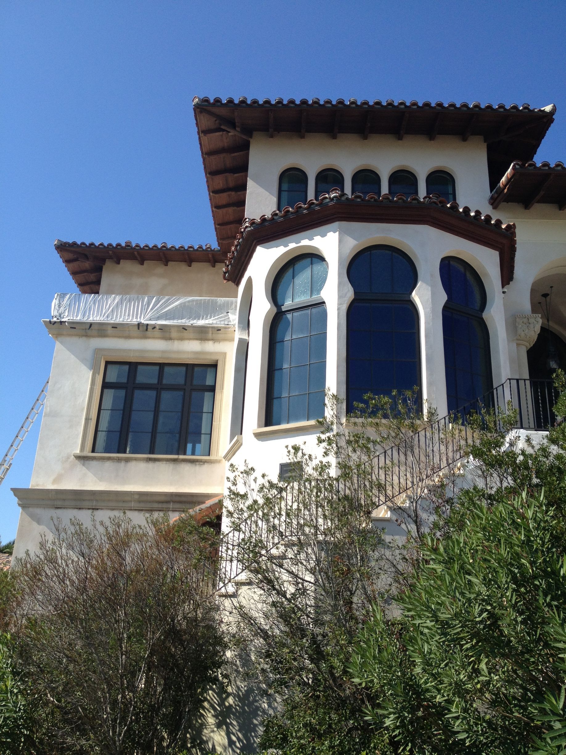 White stucco home with arched windows, tile roof, and blue sky.