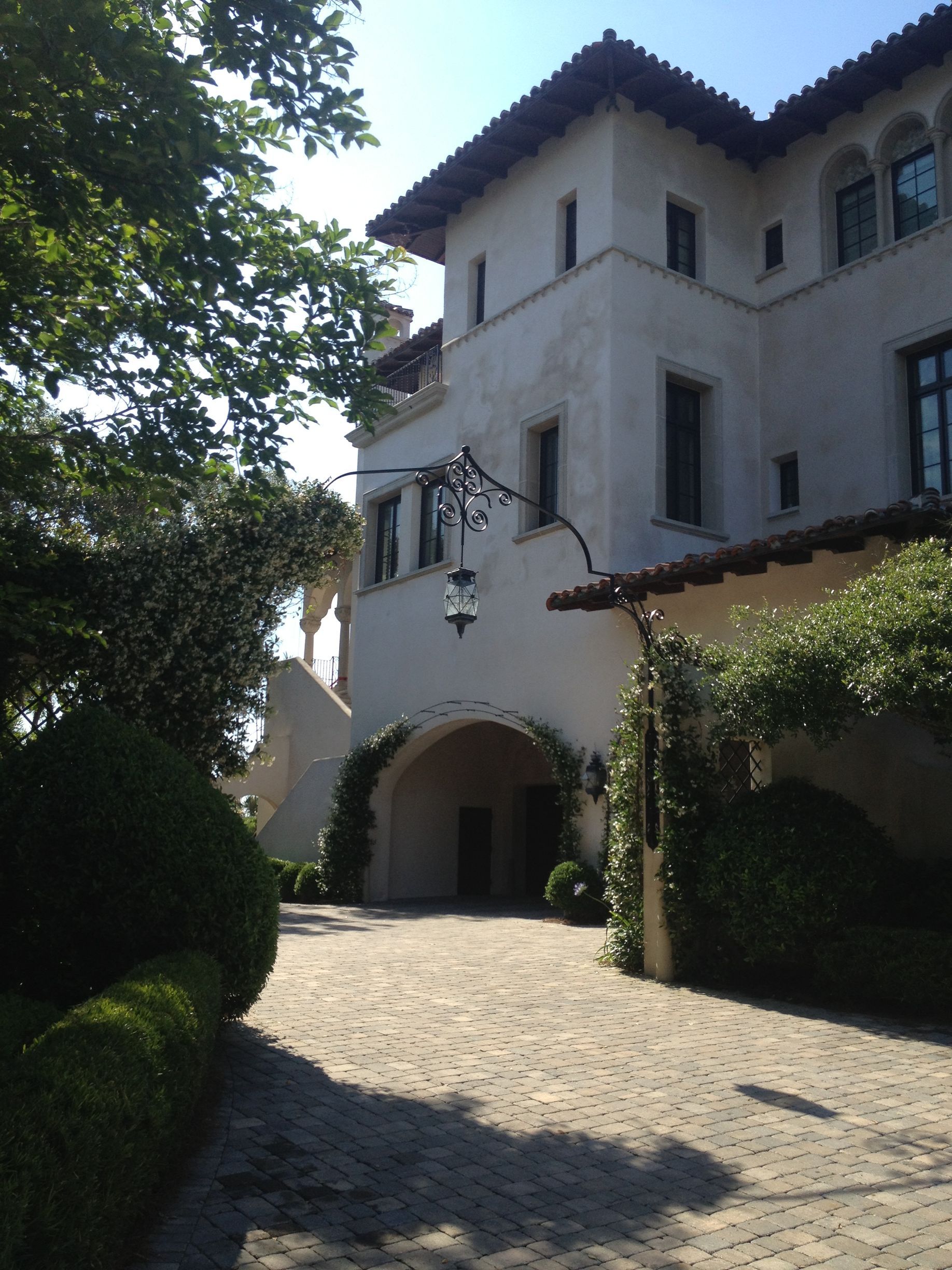 A white stucco building with a tiled roof and arched entrance on a cobblestone driveway.