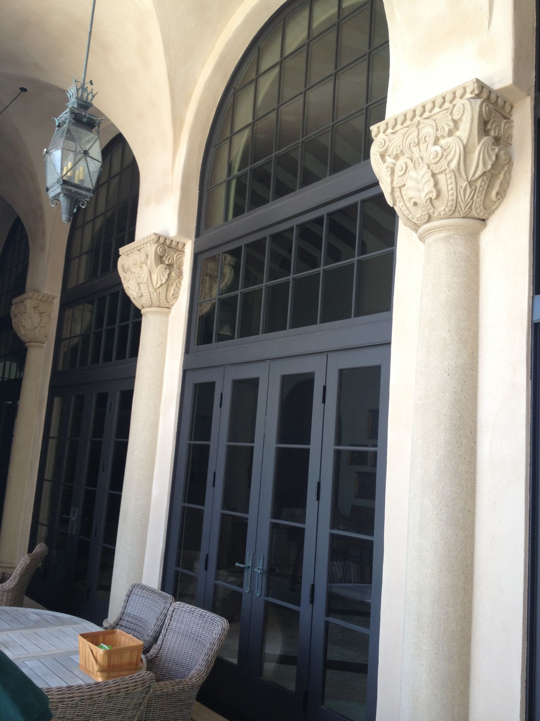 Arched doorway with dark gray framed glass doors and decorative columns on a light-colored stucco exterior.