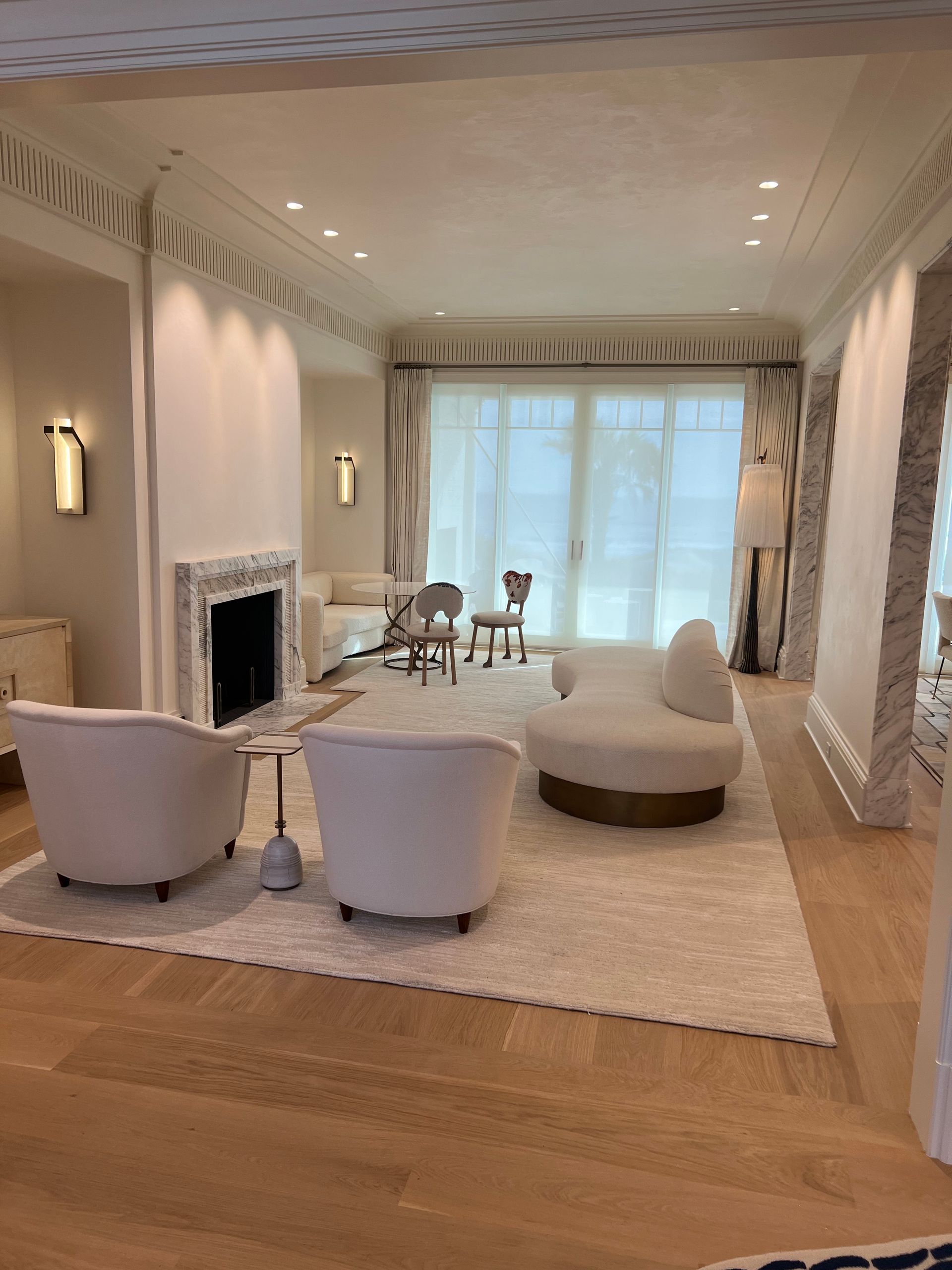 Living room with white furniture, fireplace, and rug, light wood floors.