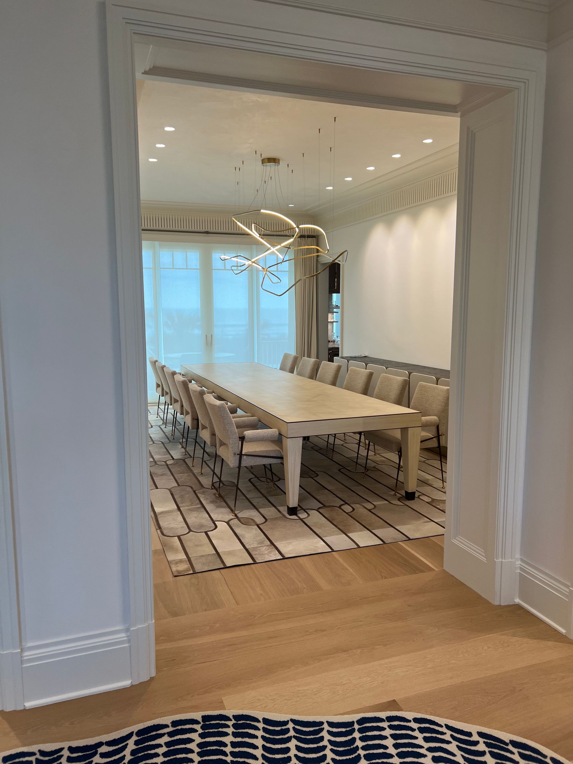 Formal dining room through a doorway, long table with chairs, overhead lighting.