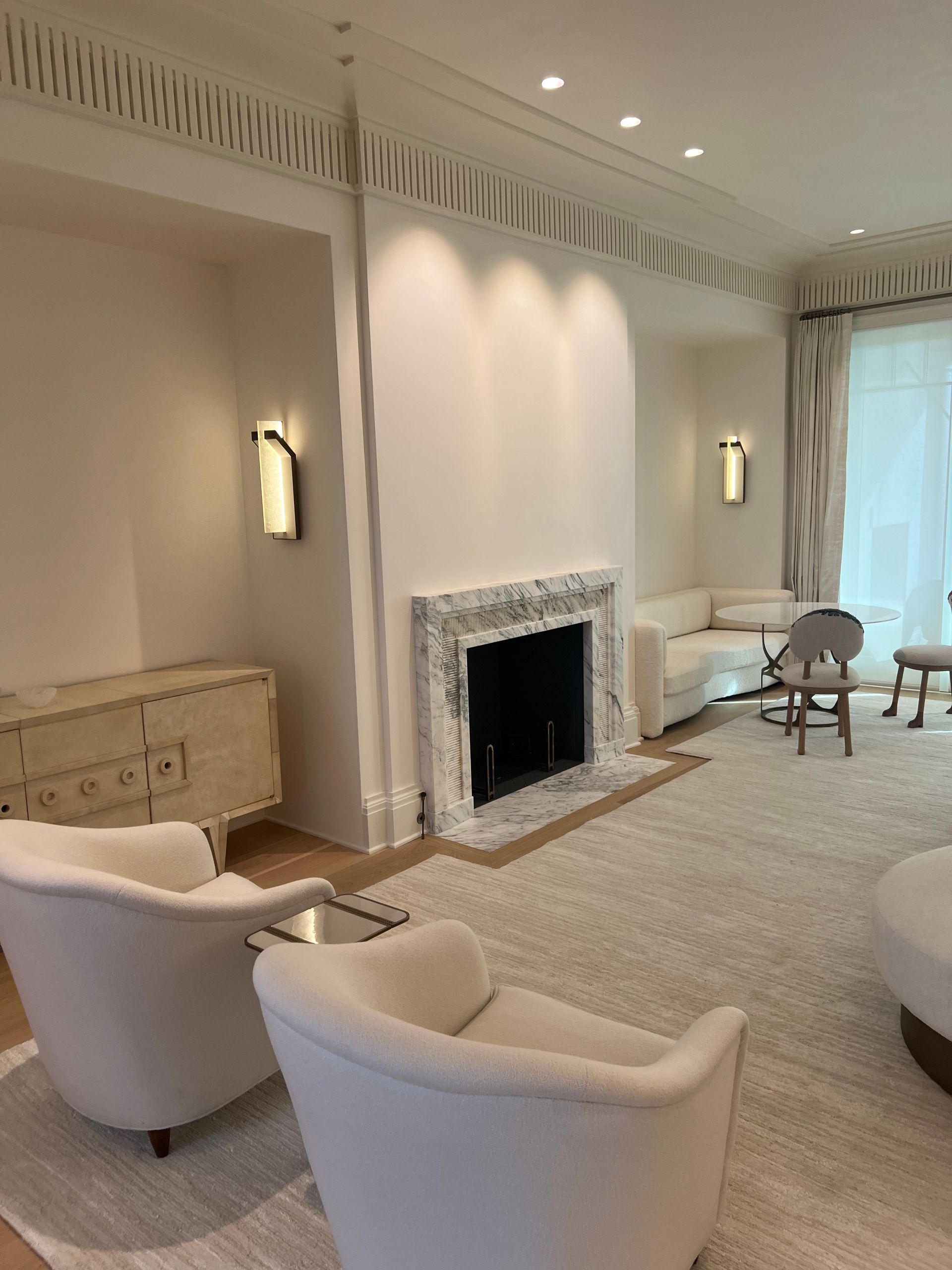 Living room with fireplace, white furniture, light walls, and patterned rug.