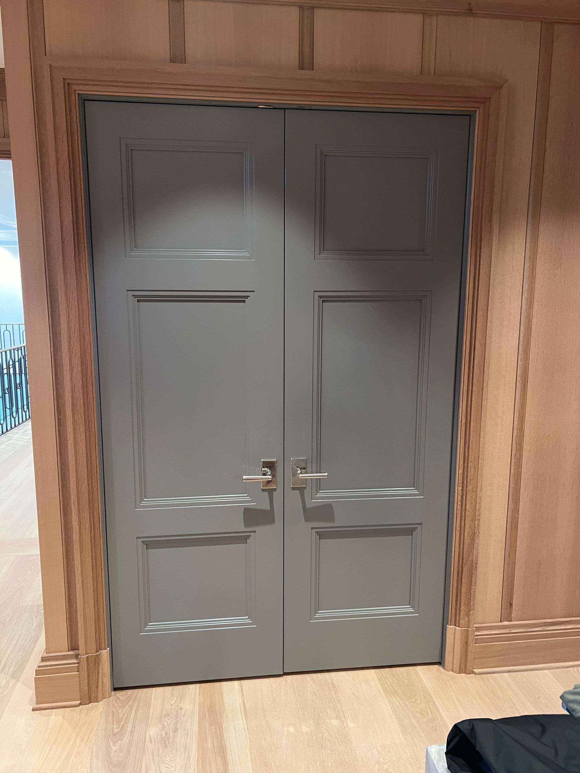Gray double doors with silver handles, framed by wood paneling.