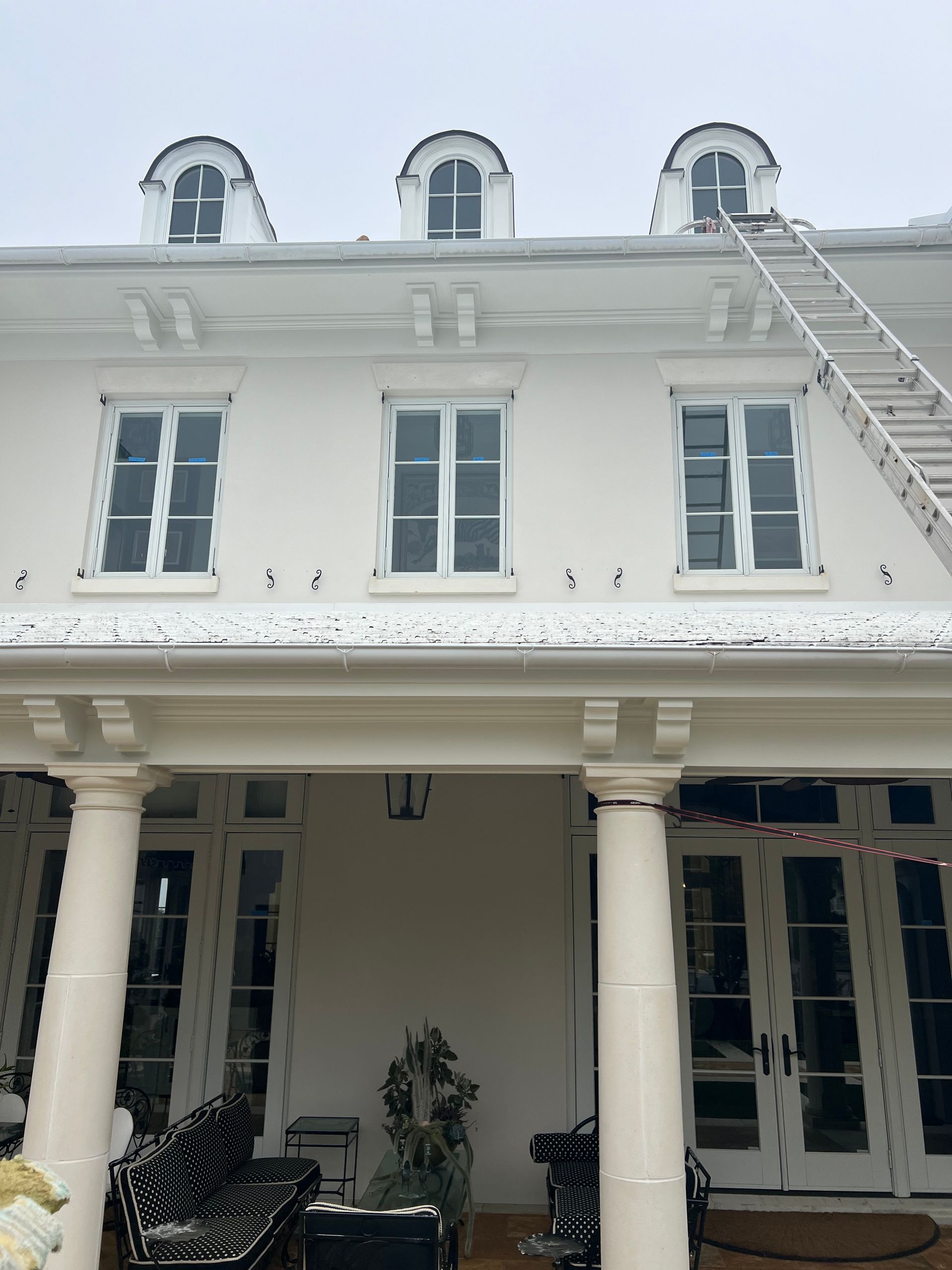 White house with arched windows and a ladder leading to the roof.