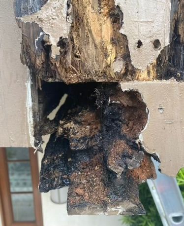 Heavily rotted wooden beam with dark, damaged sections, possibly from water damage.