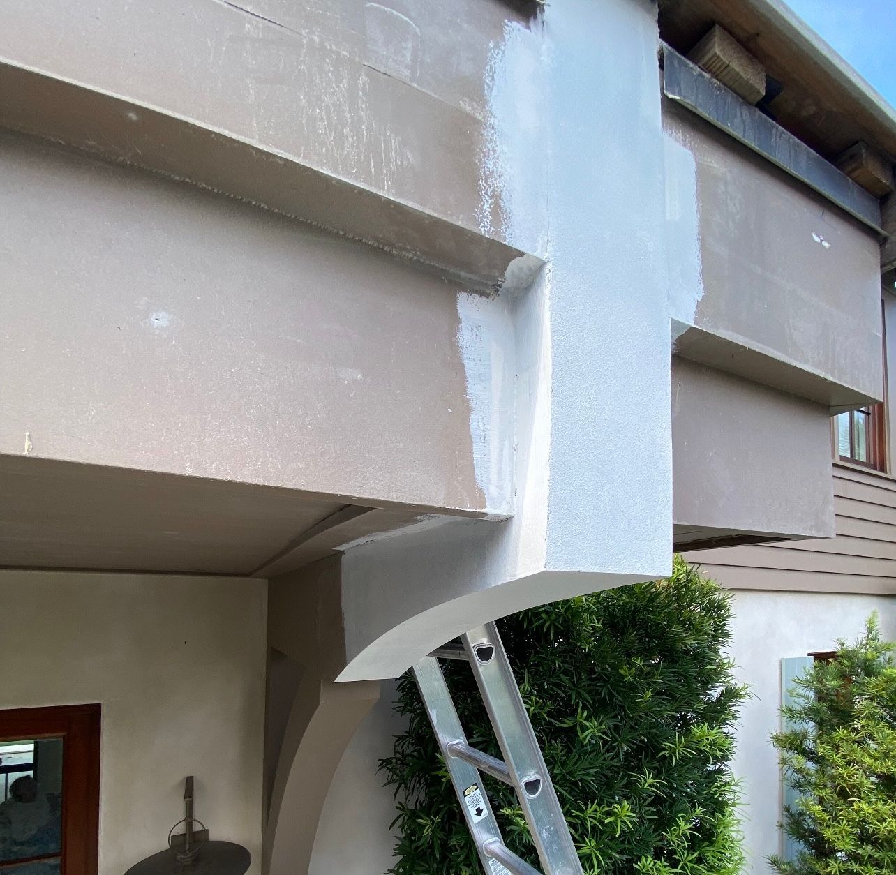 Ladder propped against a building; sections painted beige and white.