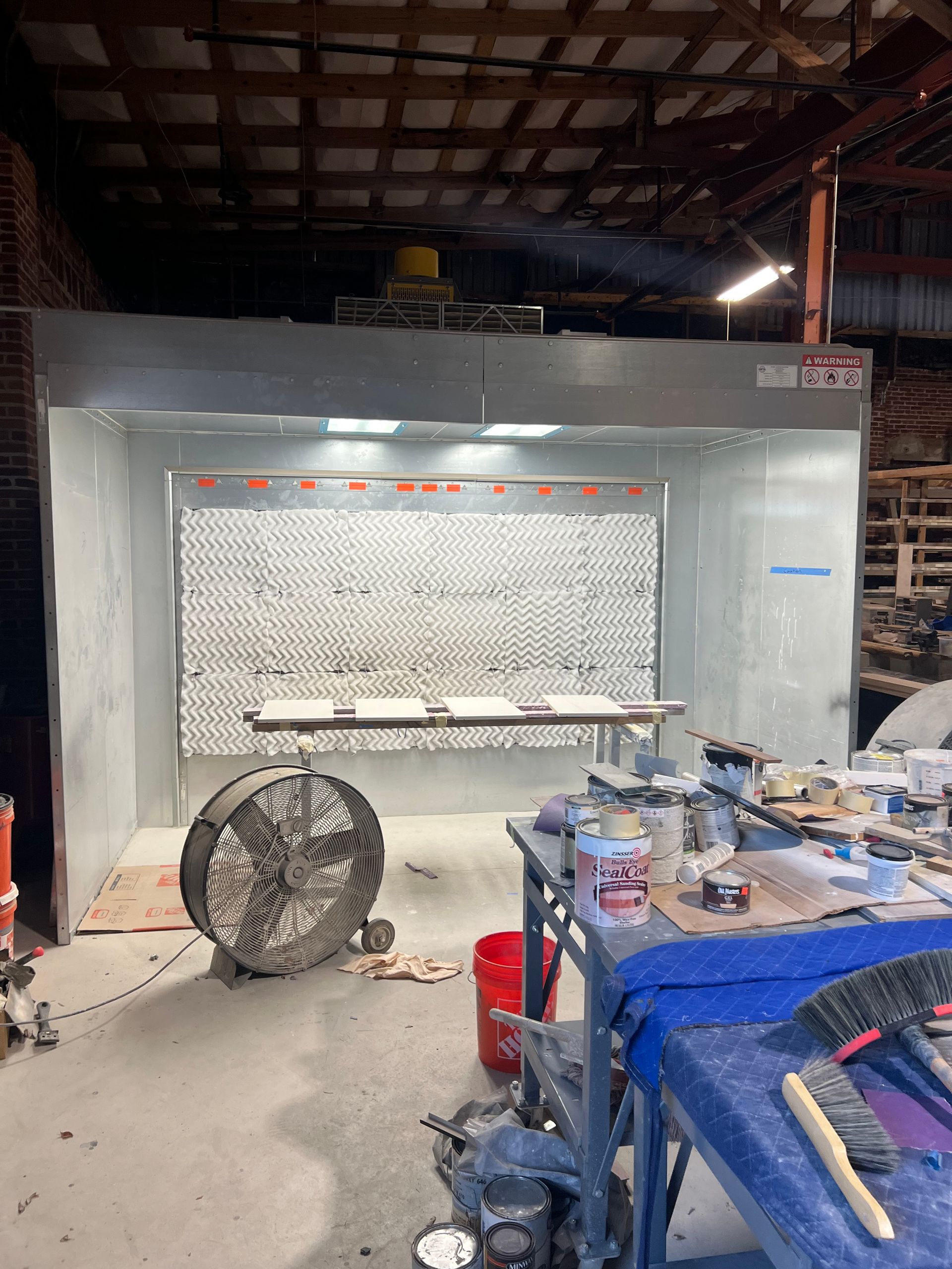 Spray paint booth in a workshop, with a fan and tools.