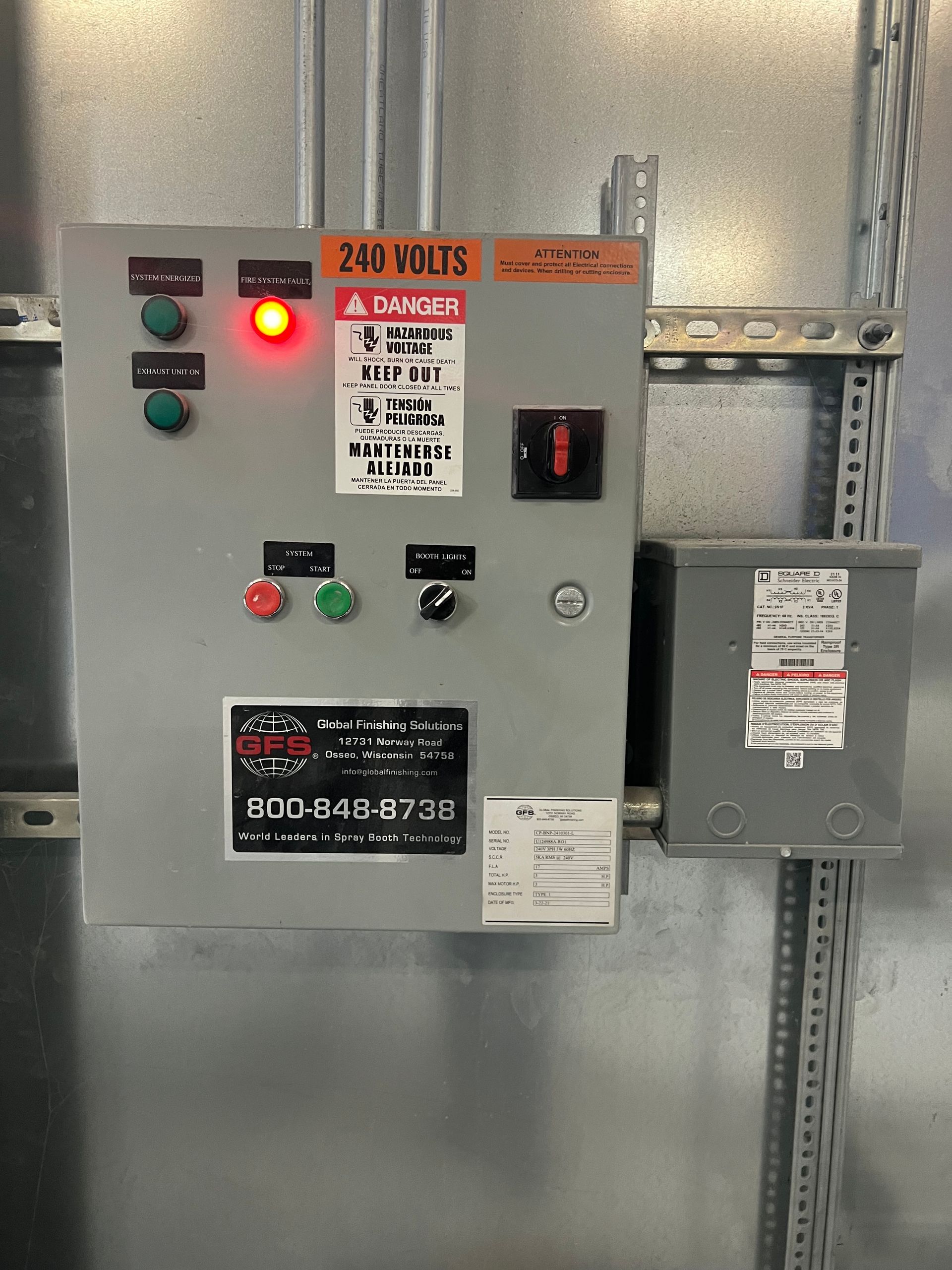 Electrical control panel with gauges, buttons, and a red light. Mounted on a metal surface.