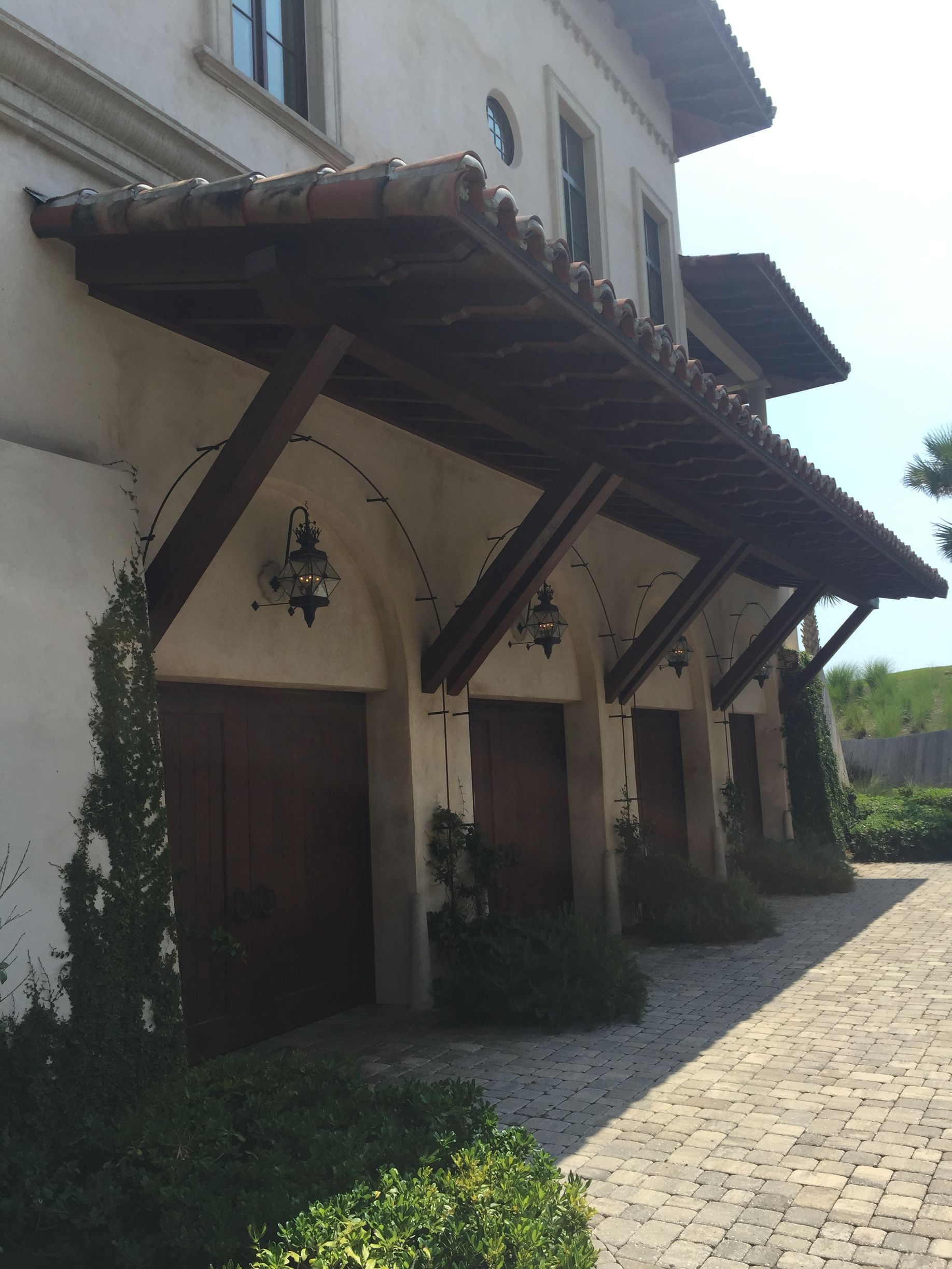 Garage doors with arched openings, each with a wooden awning and clay tile roof.