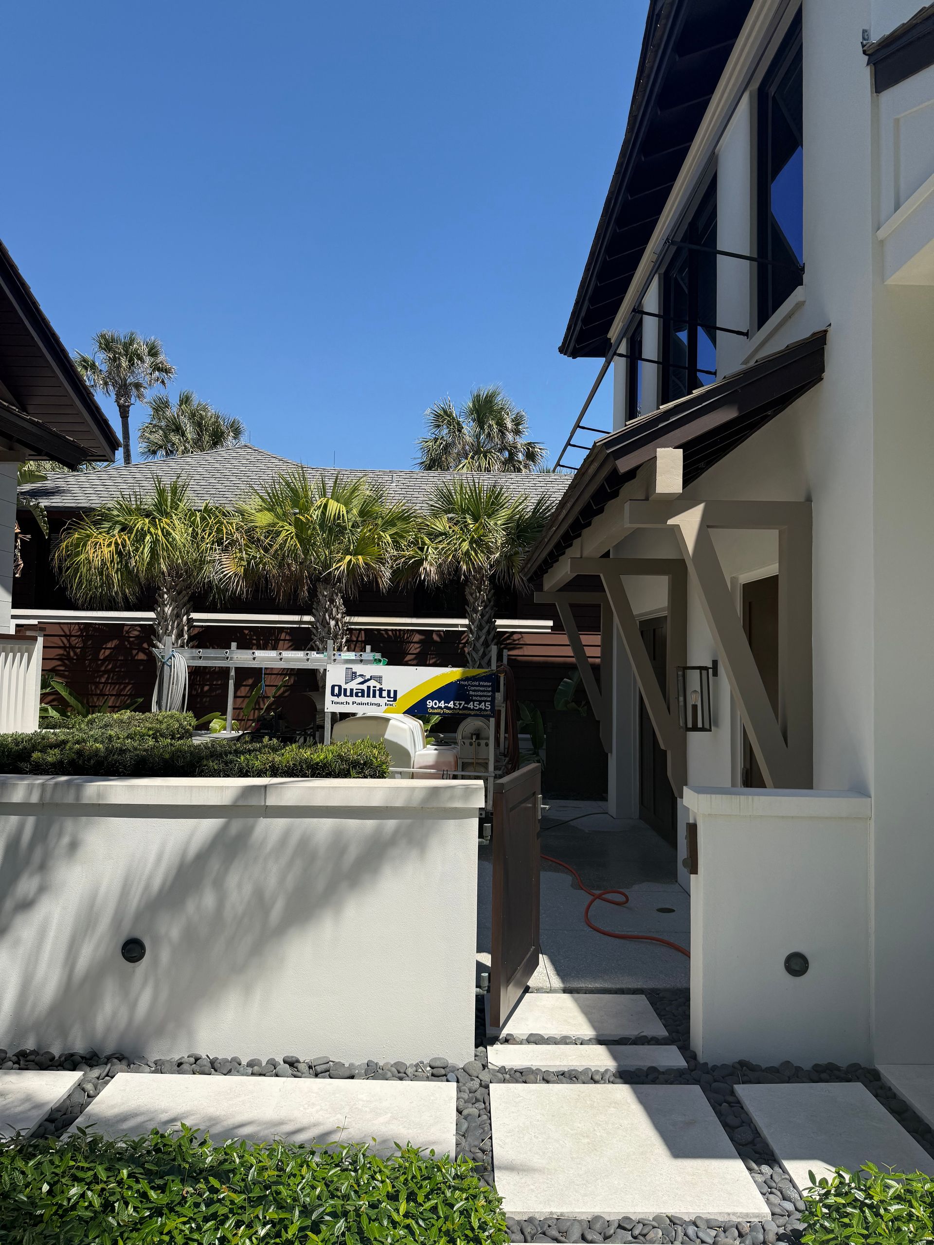 Exterior view of a modern white house with a stone pathway, landscaping, and a car visible in the driveway.