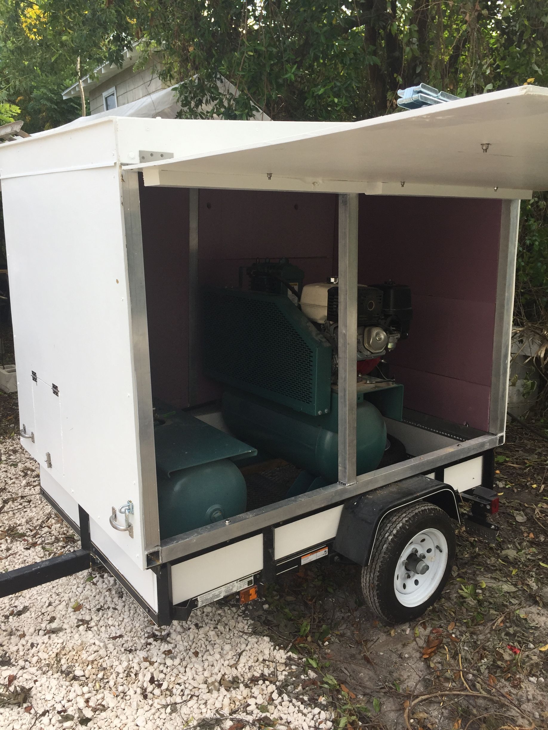 White trailer with open hatch, green air compressor inside.