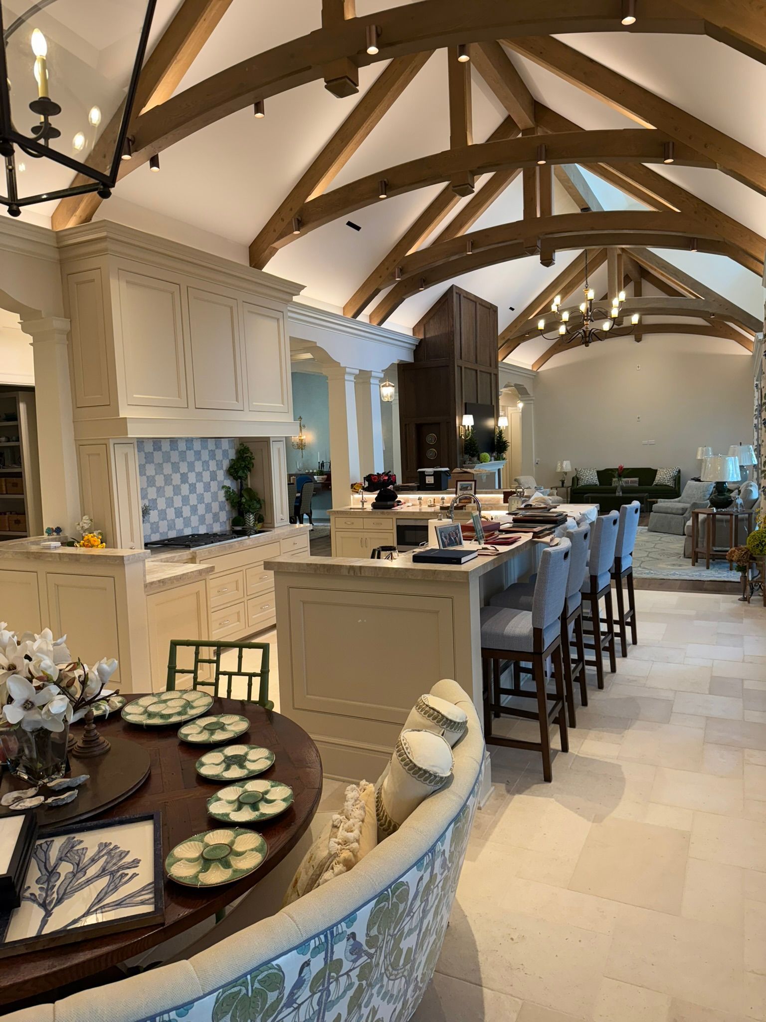 Spacious kitchen with cream cabinetry, arched ceiling, wooden beams, island with bar stools, and dining area.