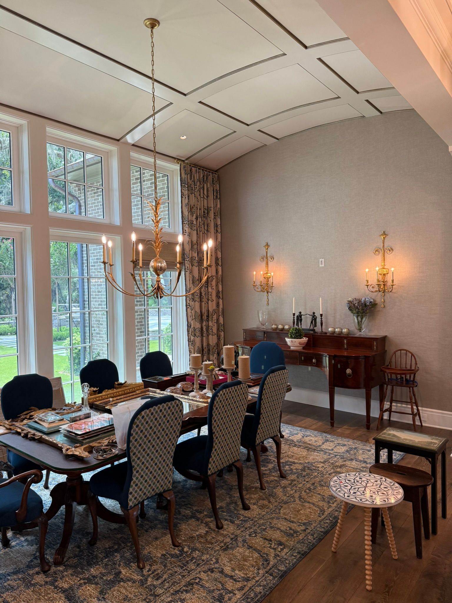 Elegant dining room with chandelier, table set for a meal, large windows, and patterned rug.