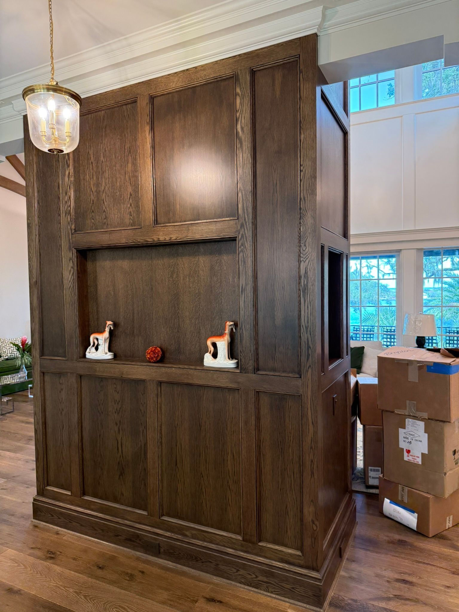 Dark wood built-in cabinet with a shelf holding two figurines. Boxes sit nearby.