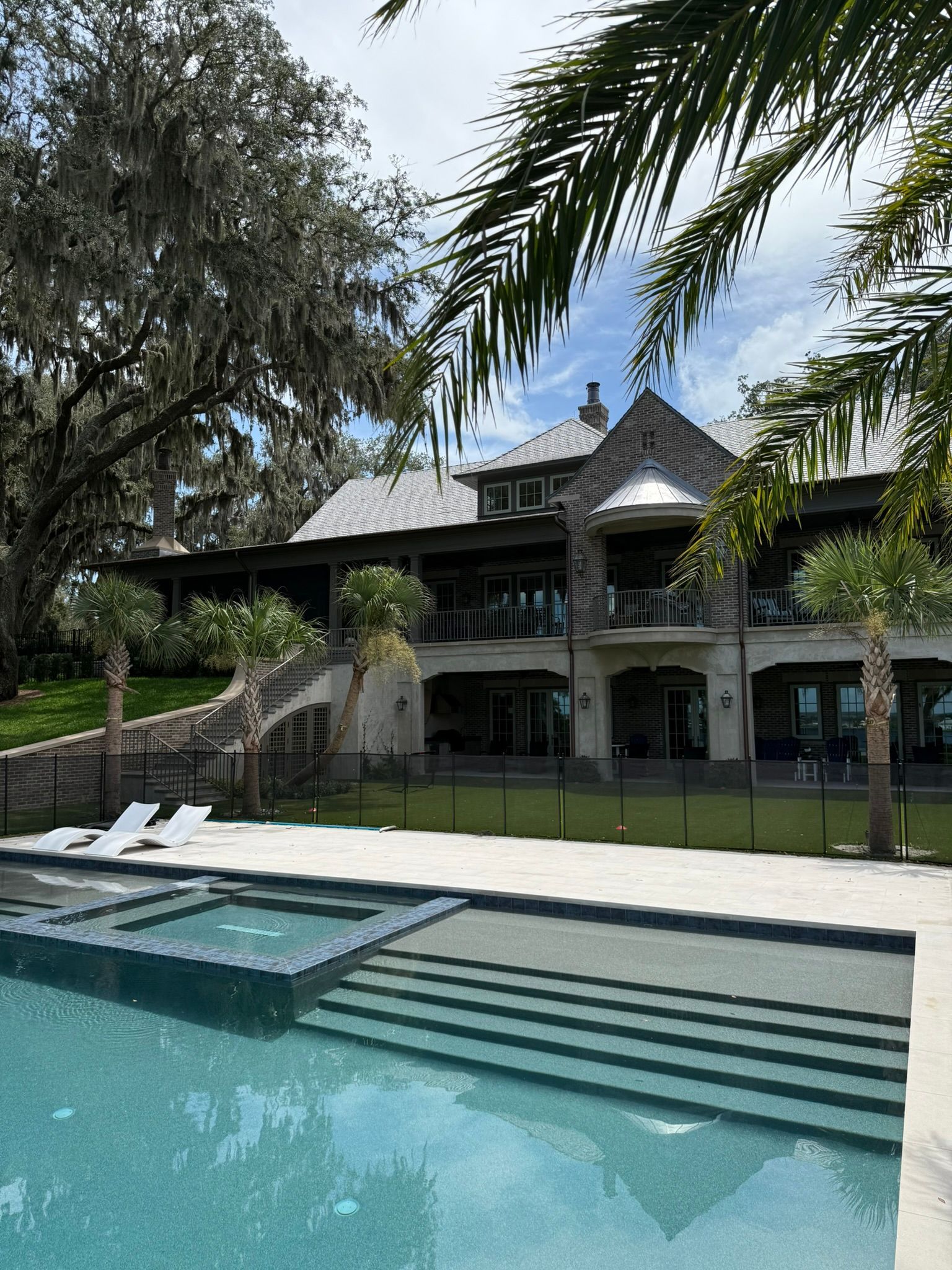 Large house with pool; palm trees frame the building.