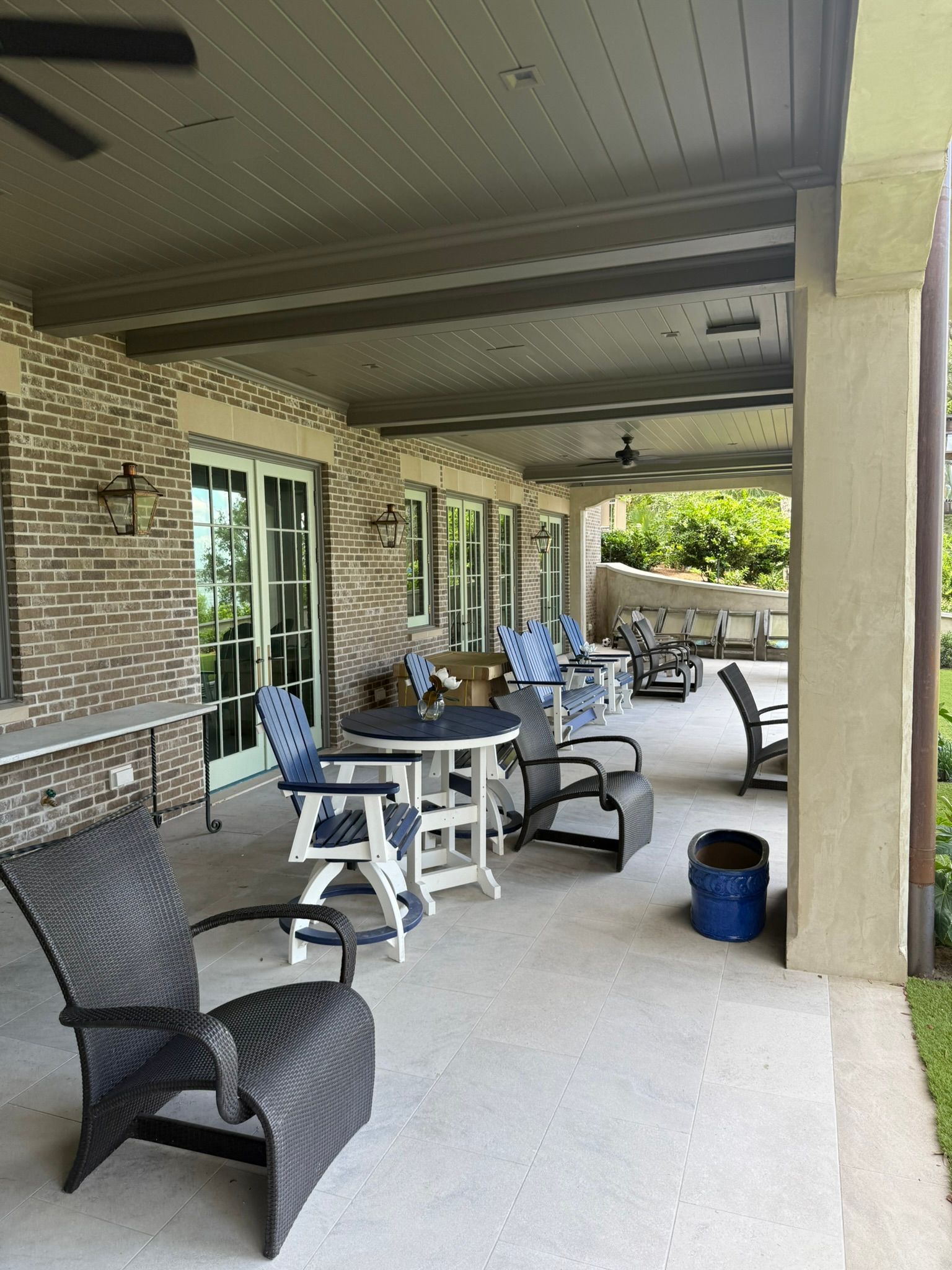 Patio with seating, brick wall, and dark ceiling. Multiple chairs around tables. Outdoor space.